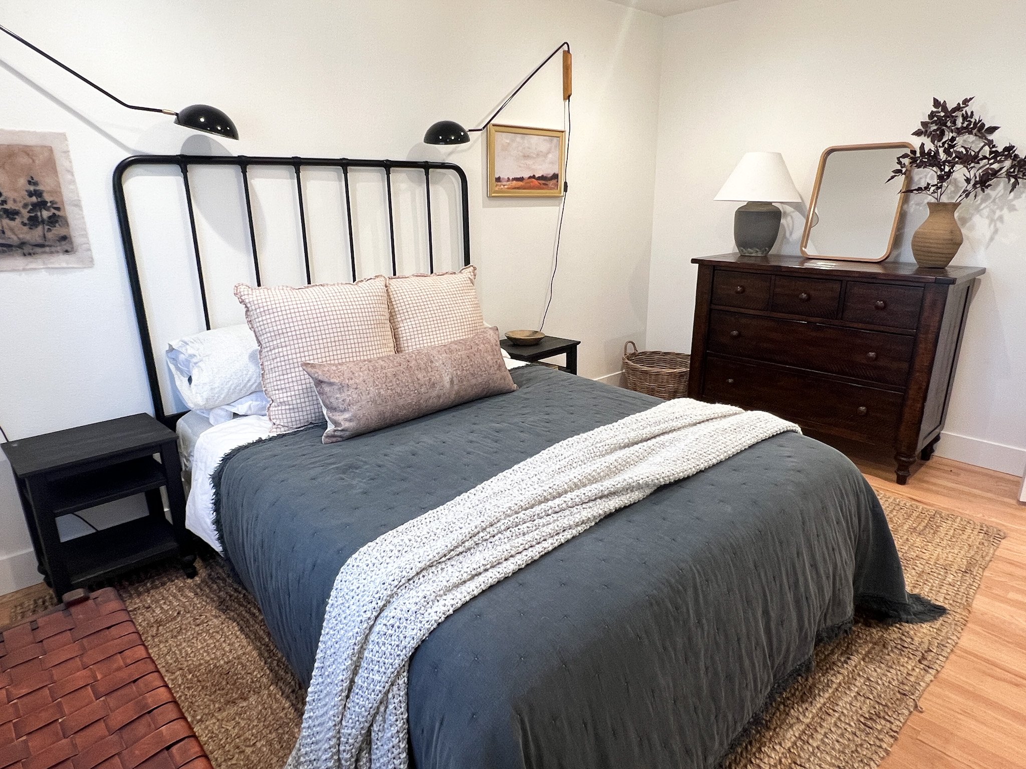Iron black headboard, queen bed, brown dresser and nightstands on a jute rug