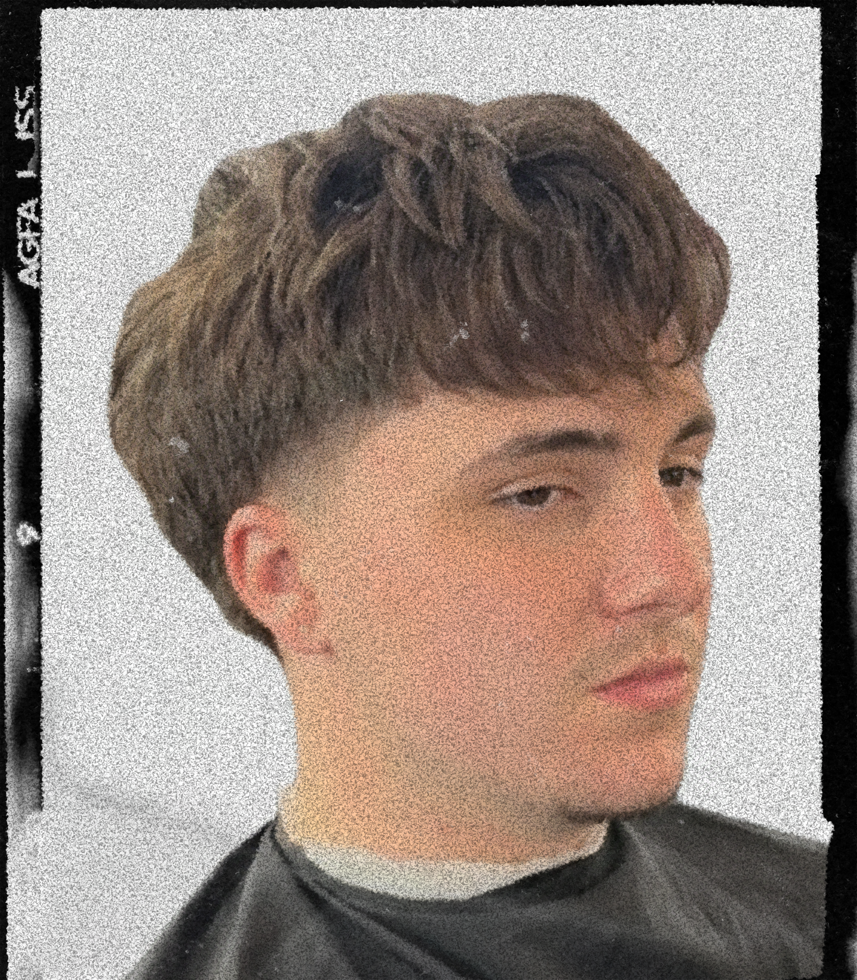 Young person with short brown hair getting a haircut, wearing a black barber cape.