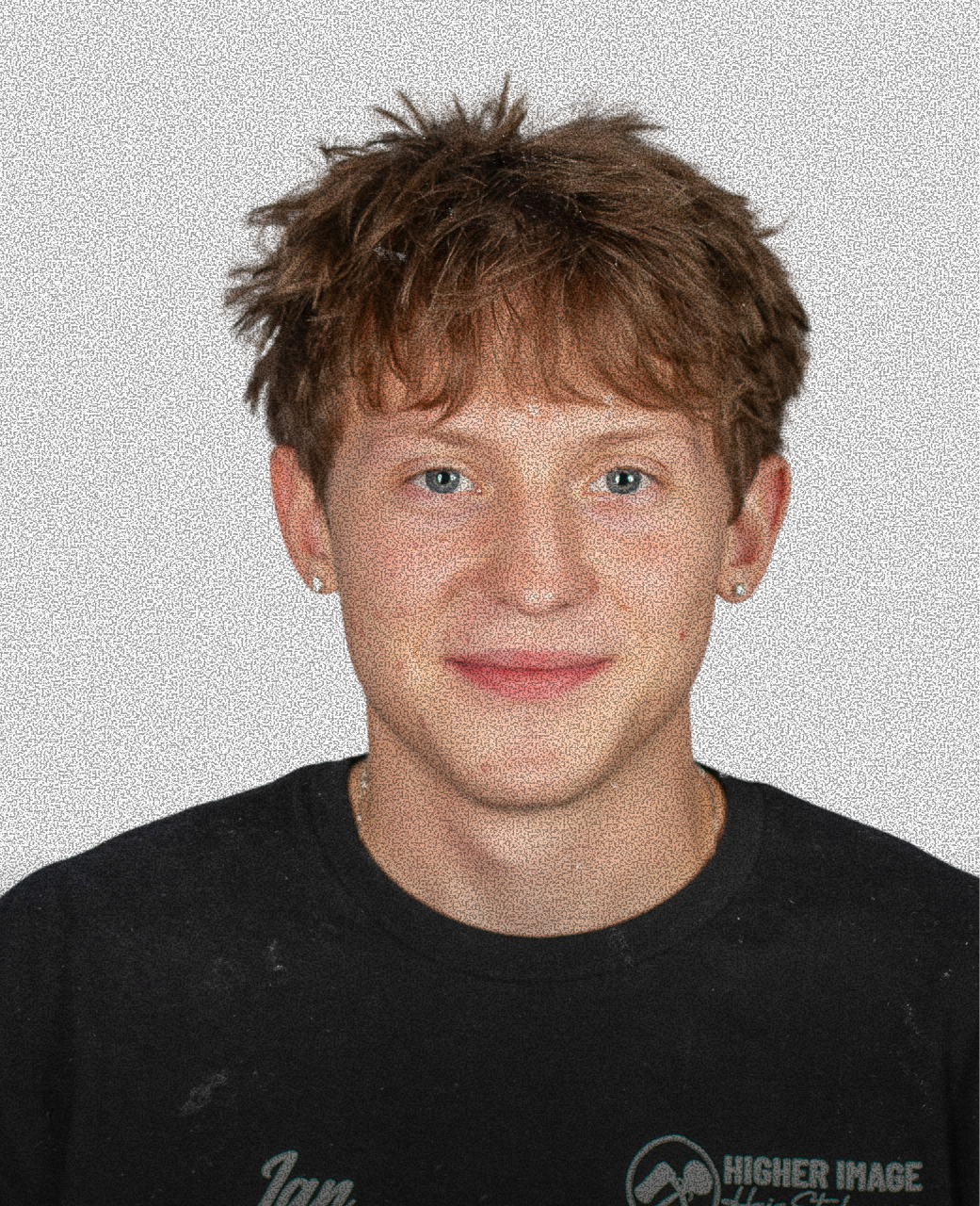 A young person with short, messy brown hair and blue eyes, wearing a black t-shirt and earrings, smiling at the camera against a plain background.