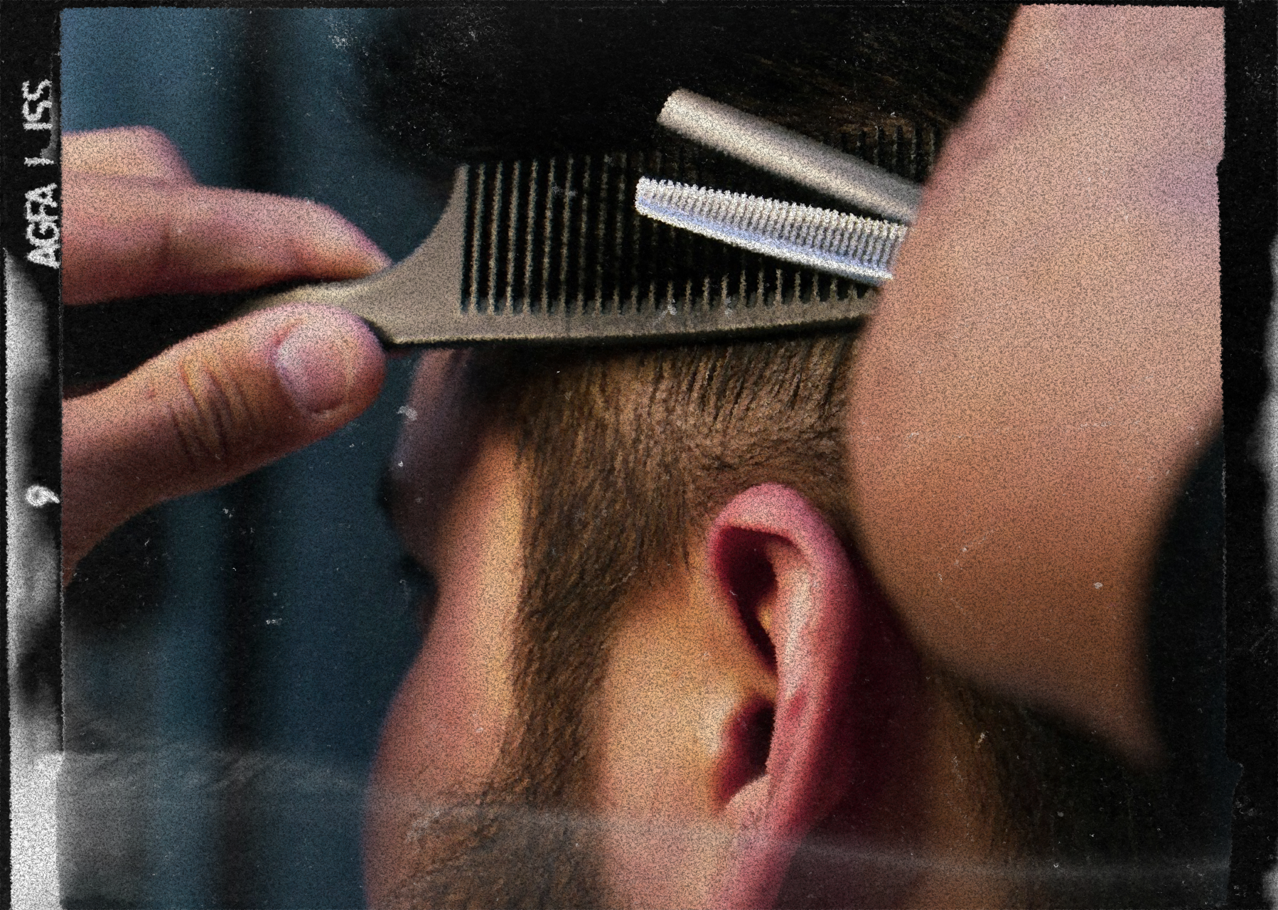 Barber trimming a man's beard with an electric trimmer, close-up view.