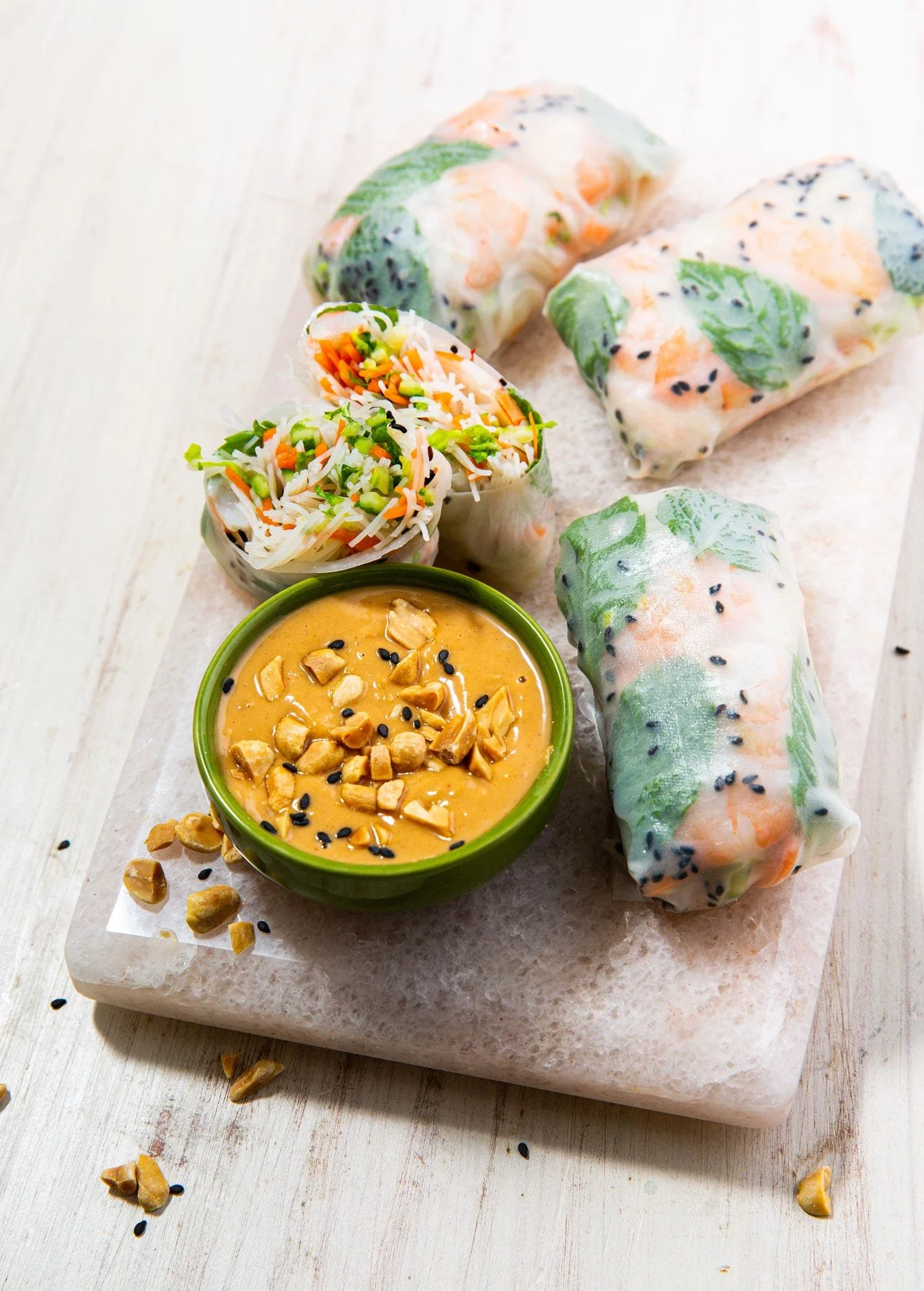 Fresh rice paper rolls arranged beside a bowl of peanut dipping sauce