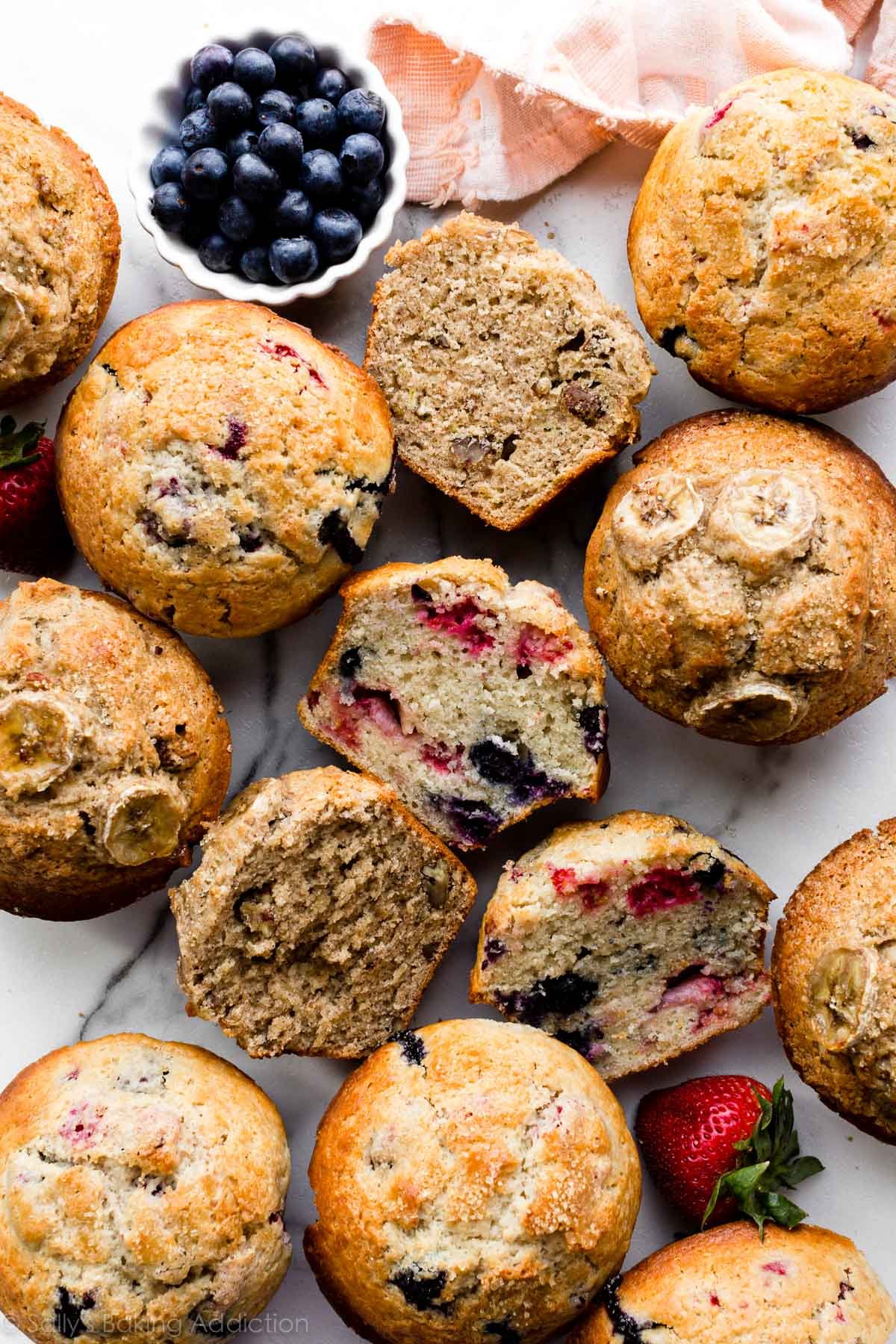 Assorted muffins with fruit and berries on a serving surface