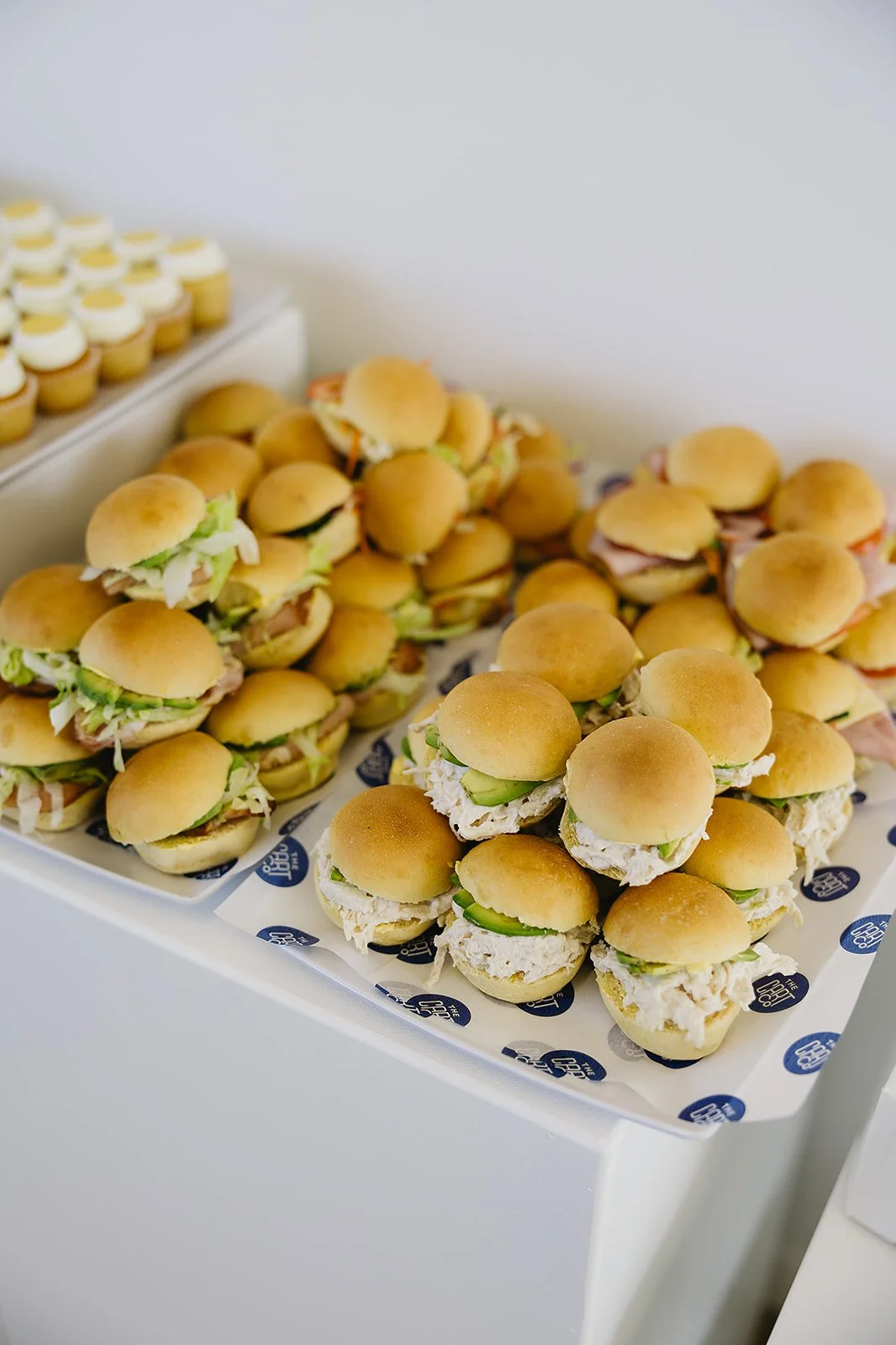 Assorted mini sliders with lettuce, cucumber and fillings served on platters
