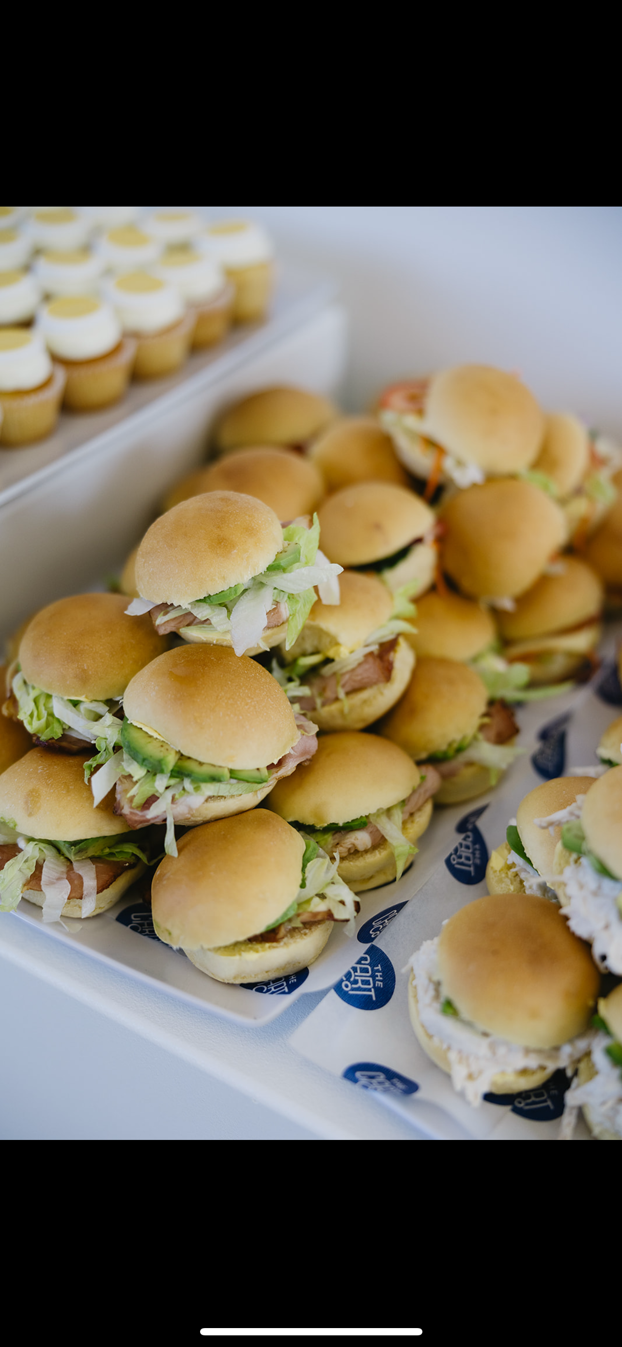 Assorted mini sliders with lettuce, cucumber and fillings served on platters