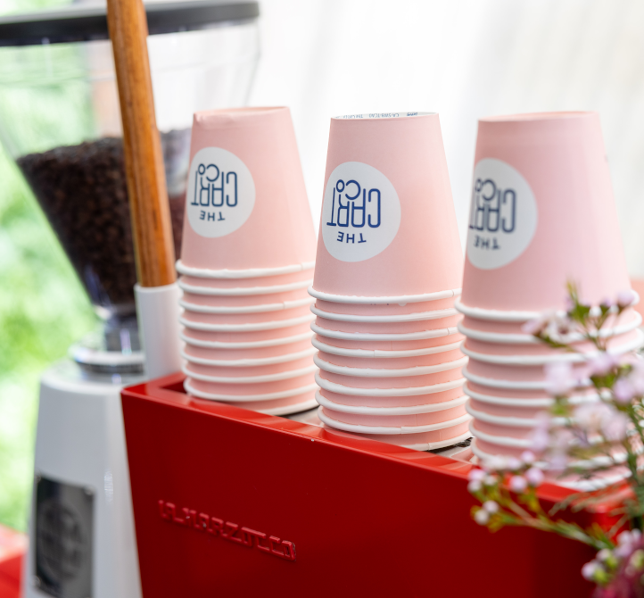 Stacks of pink The Cart Co takeaway cups on a red espresso machine