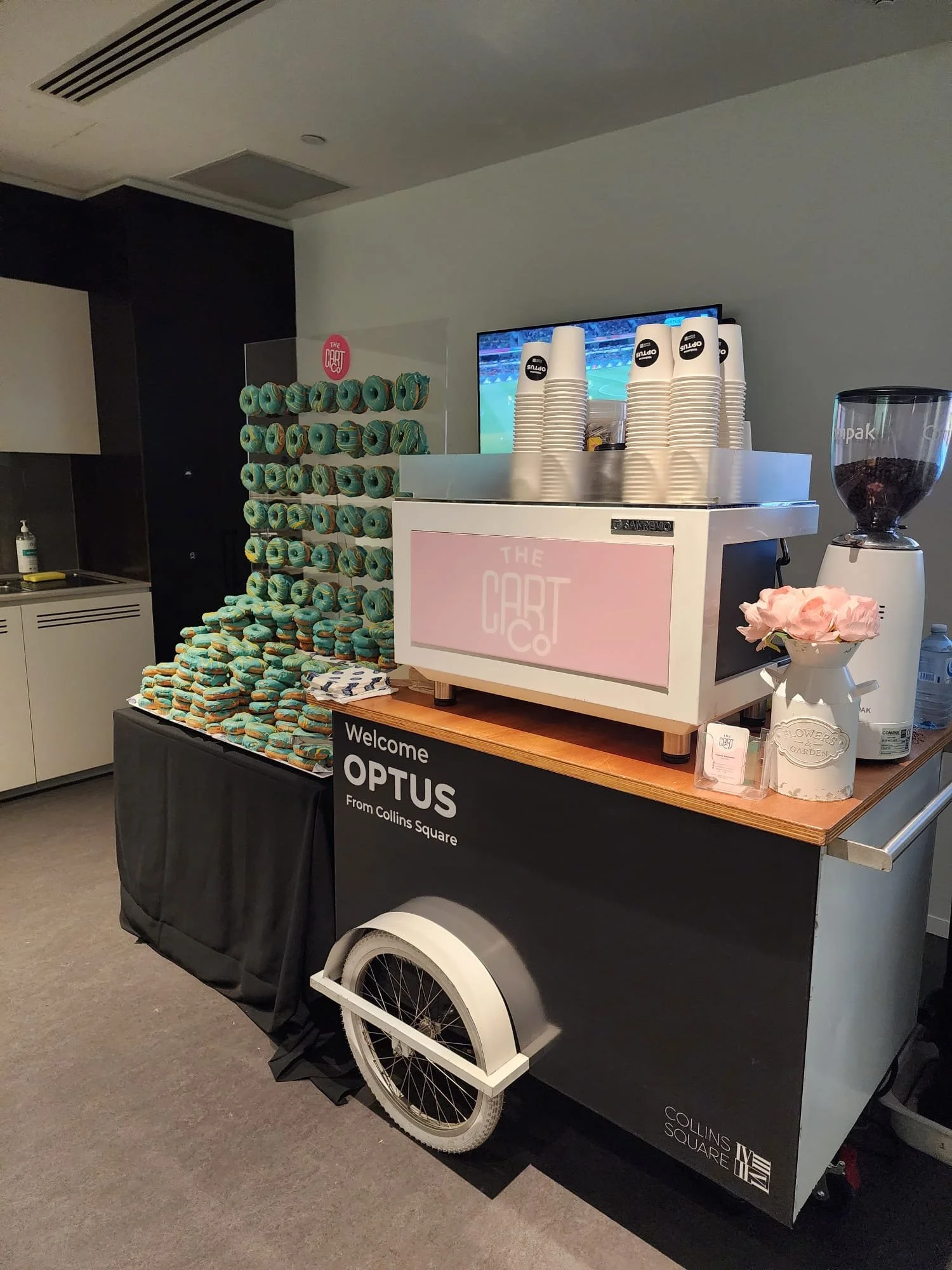The Cart Co coffee cart beside a wall of blue iced donuts at an OPTUS event