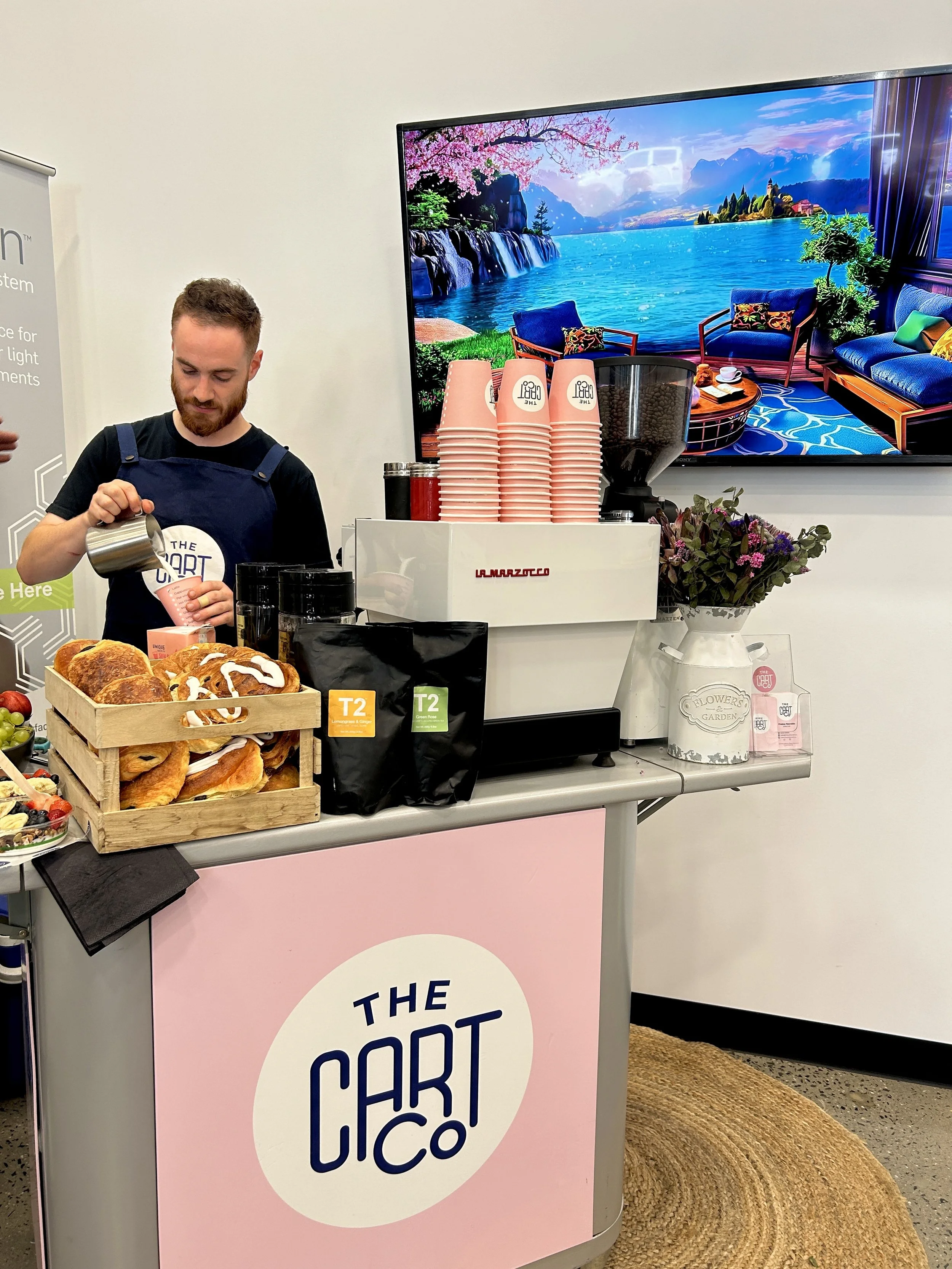 Barista preparing fresh coffee at The Cart Co mobile coffee cart during an indoor event