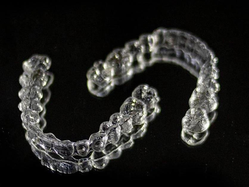 Two clear aligner trays are displayed on a black background