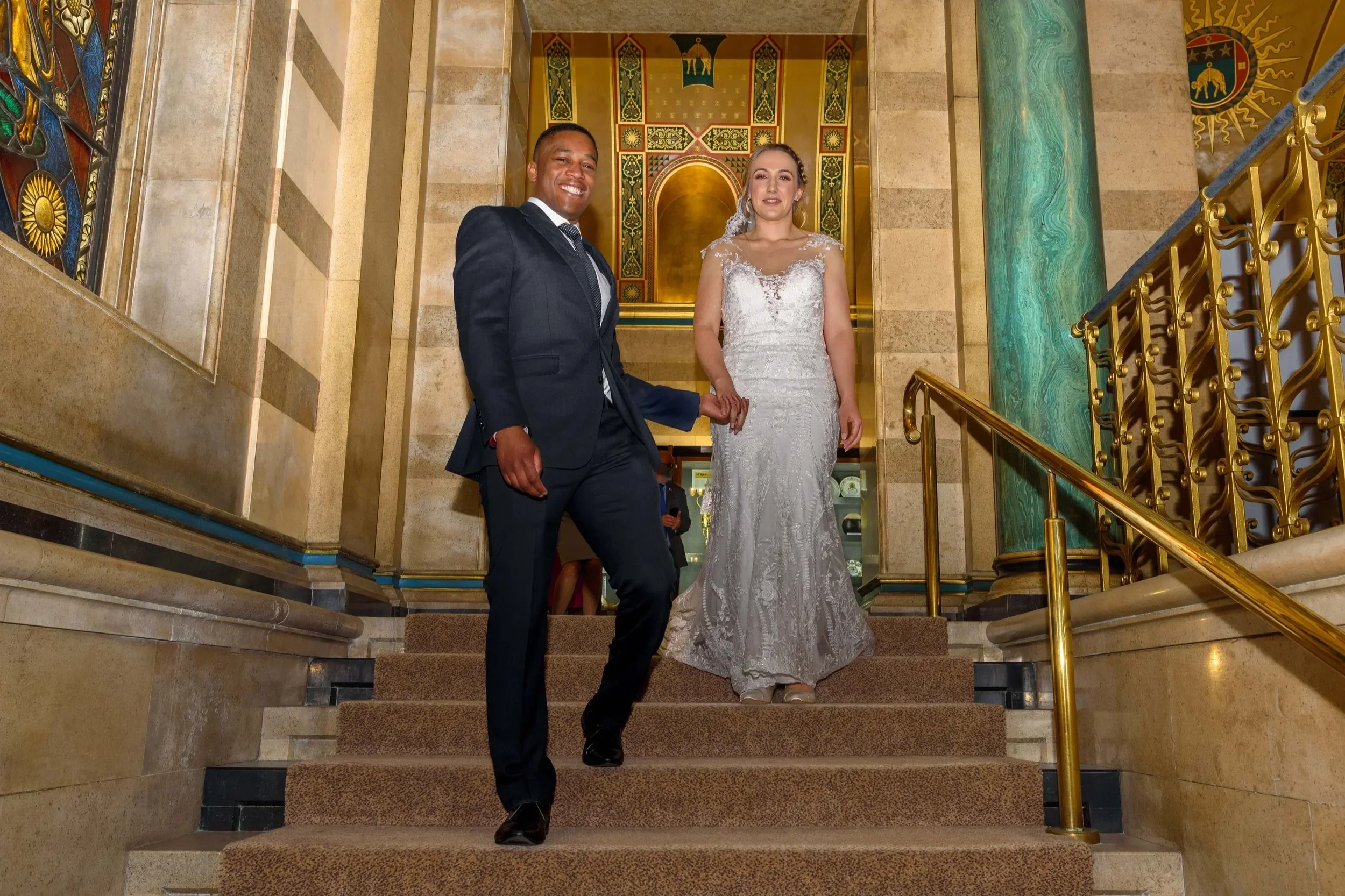 Interracial newlyweds on staircase inside Leeds Civic Hall