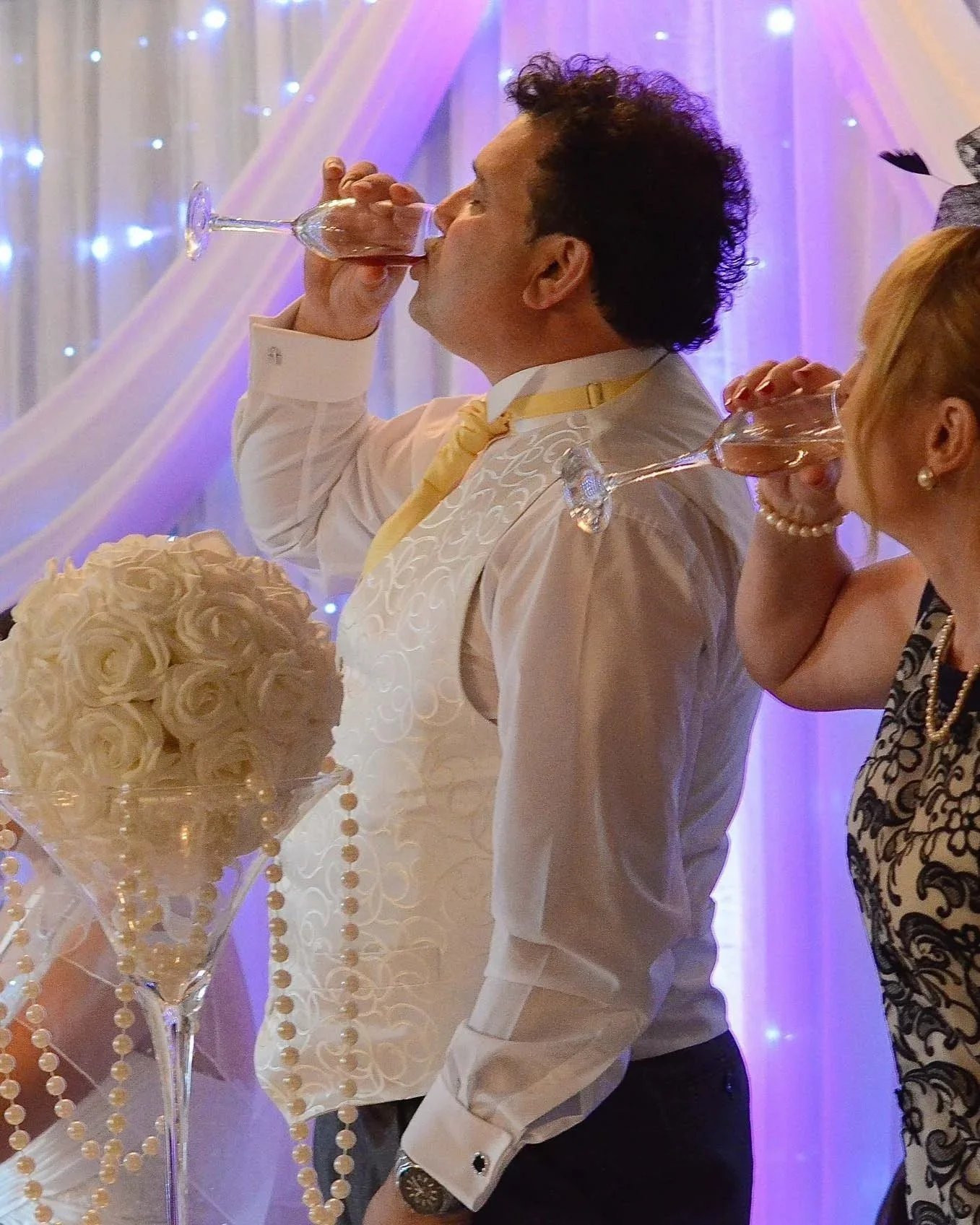 Candid photo of father and mother of the bride drinking heartfelt toast at Victoria Hotel Bradford West Yorkshire wedding. Romantic, cool ambience and setting, soft lighting, white bouquet, pearls, champagne,