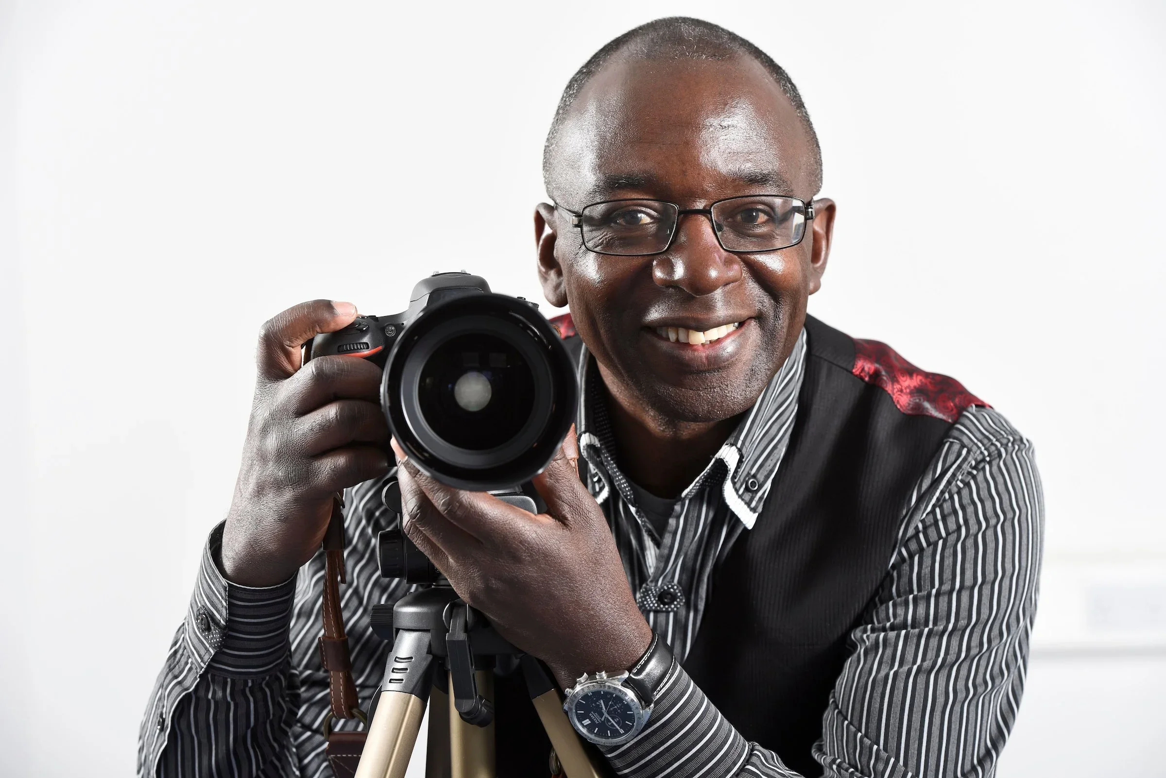 Smiling man with glasses holding a professional camera on a tripod