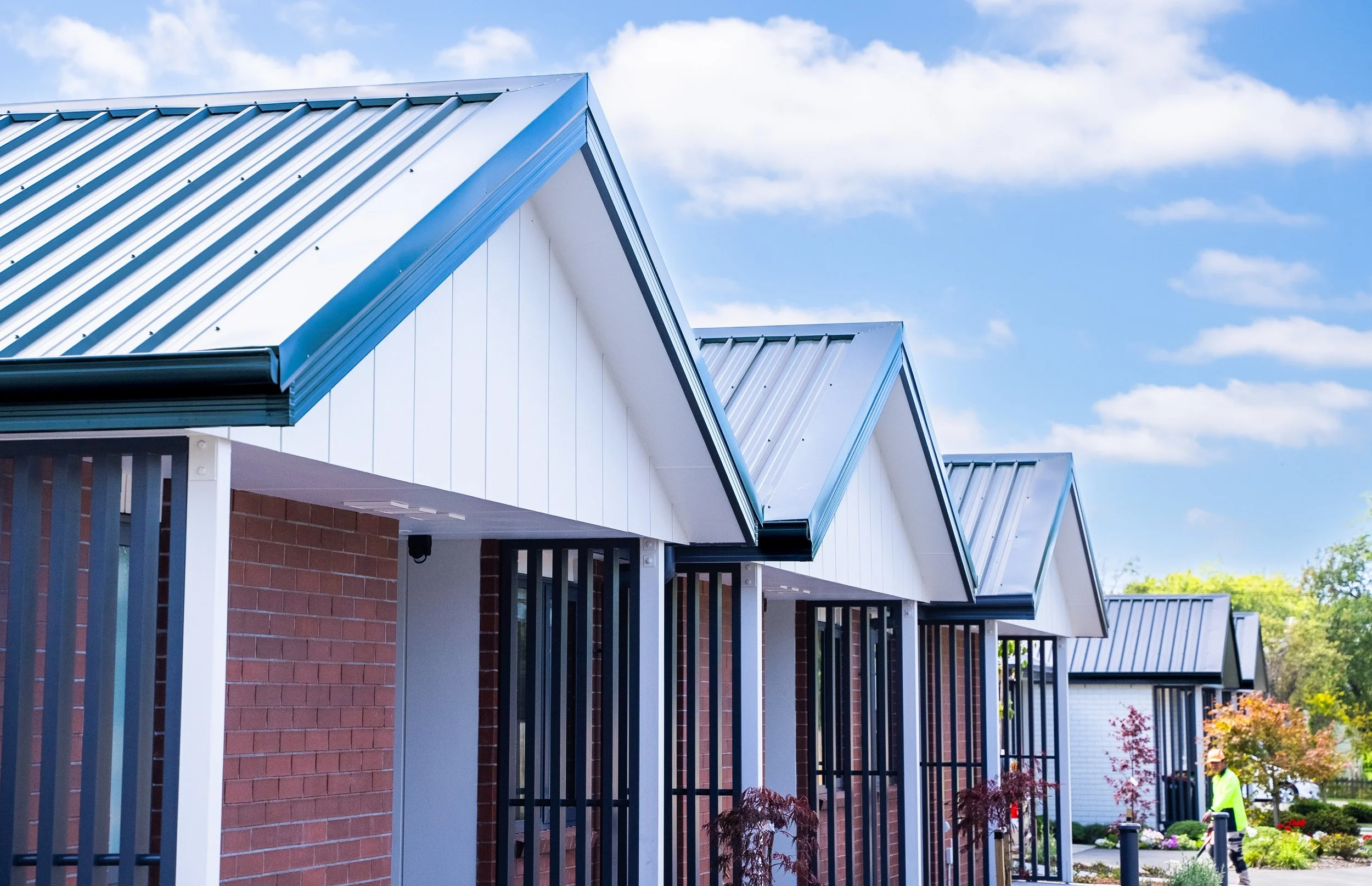 Exterior view of single-level homes opening onto communal outdoor spaces and plants.