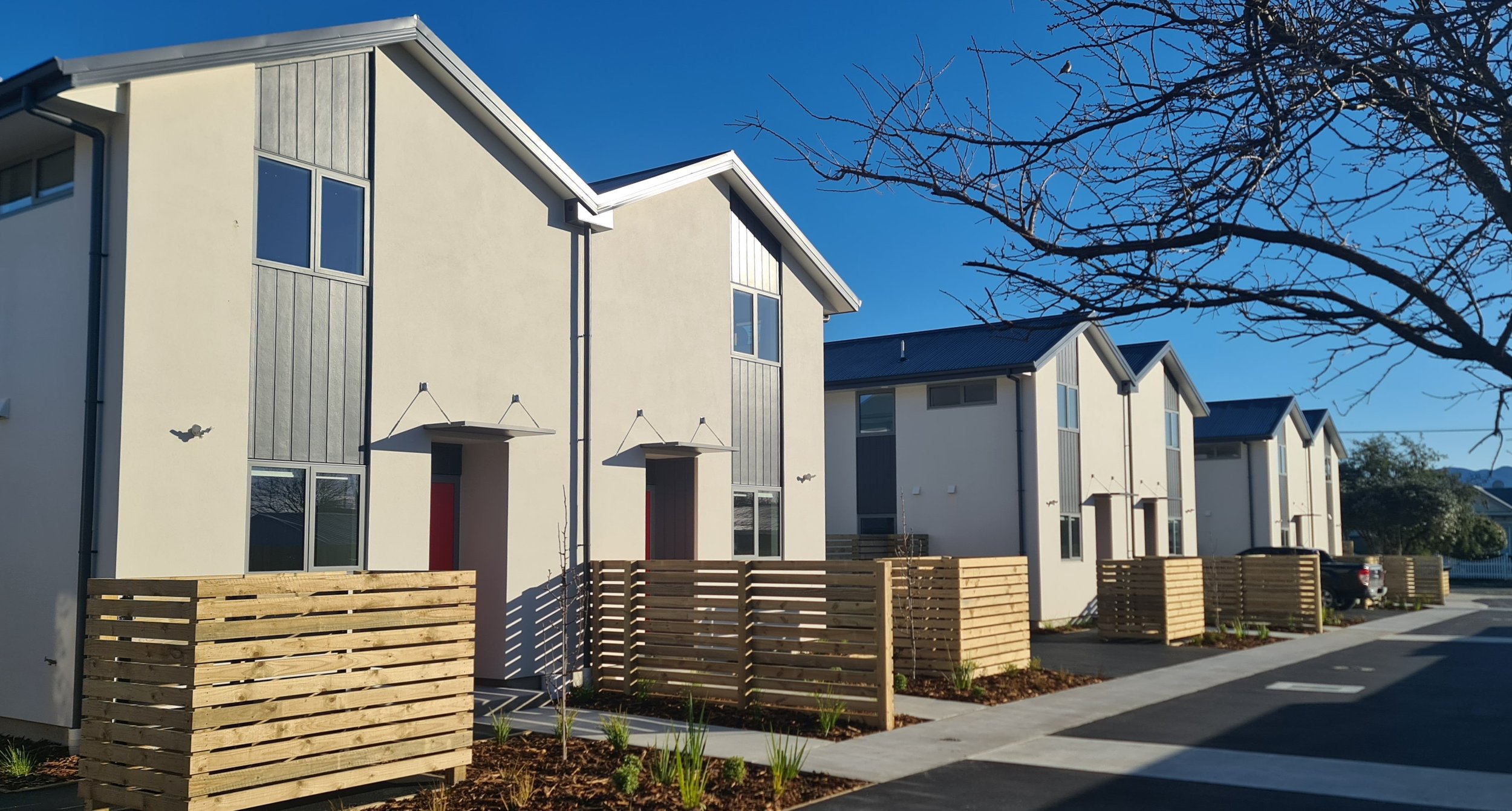 Exterior view of two-level homes opening onto communal areas and gardens.