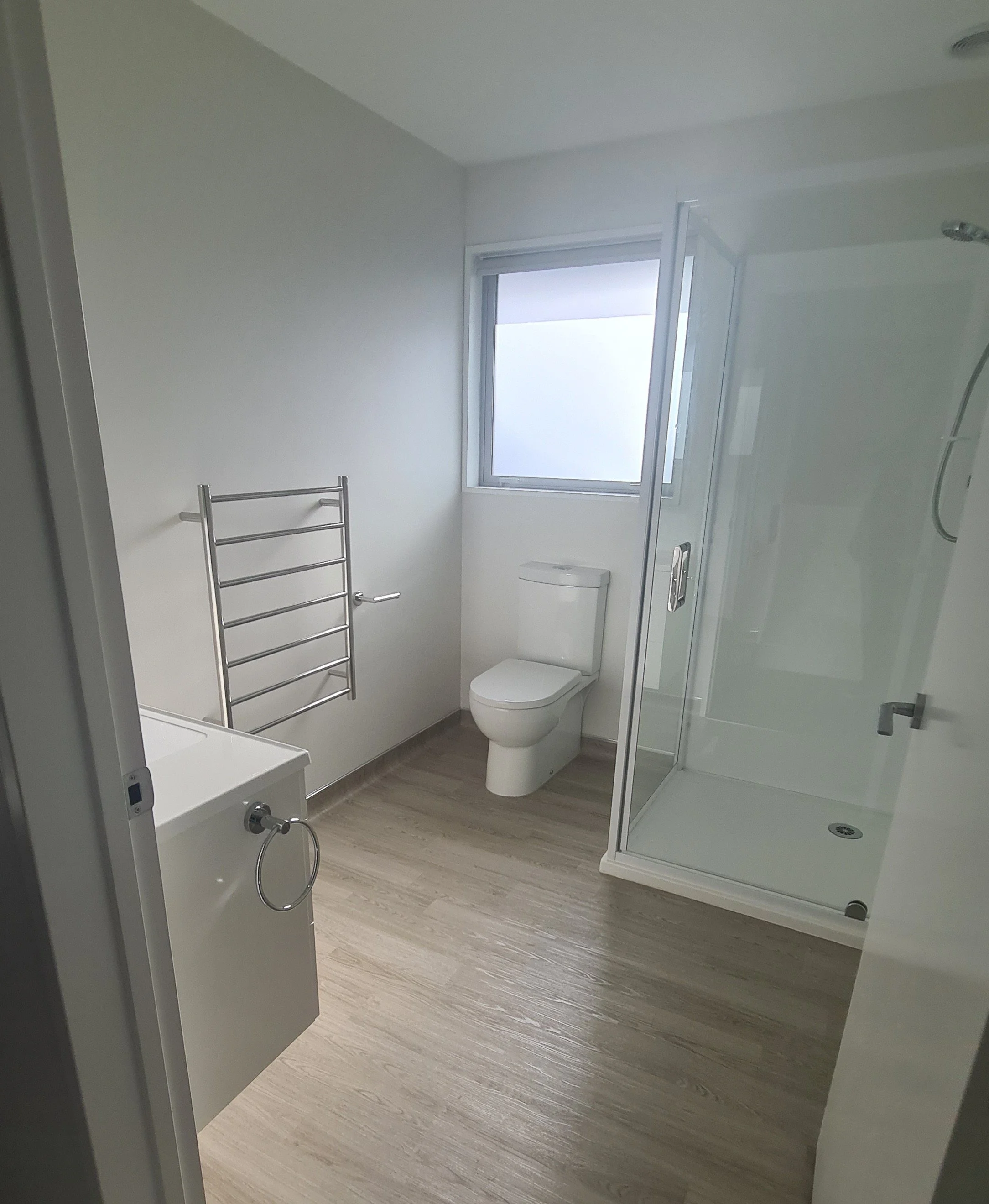 Bathroom area with laminate timber-look floor, basin, toilet, shower and window