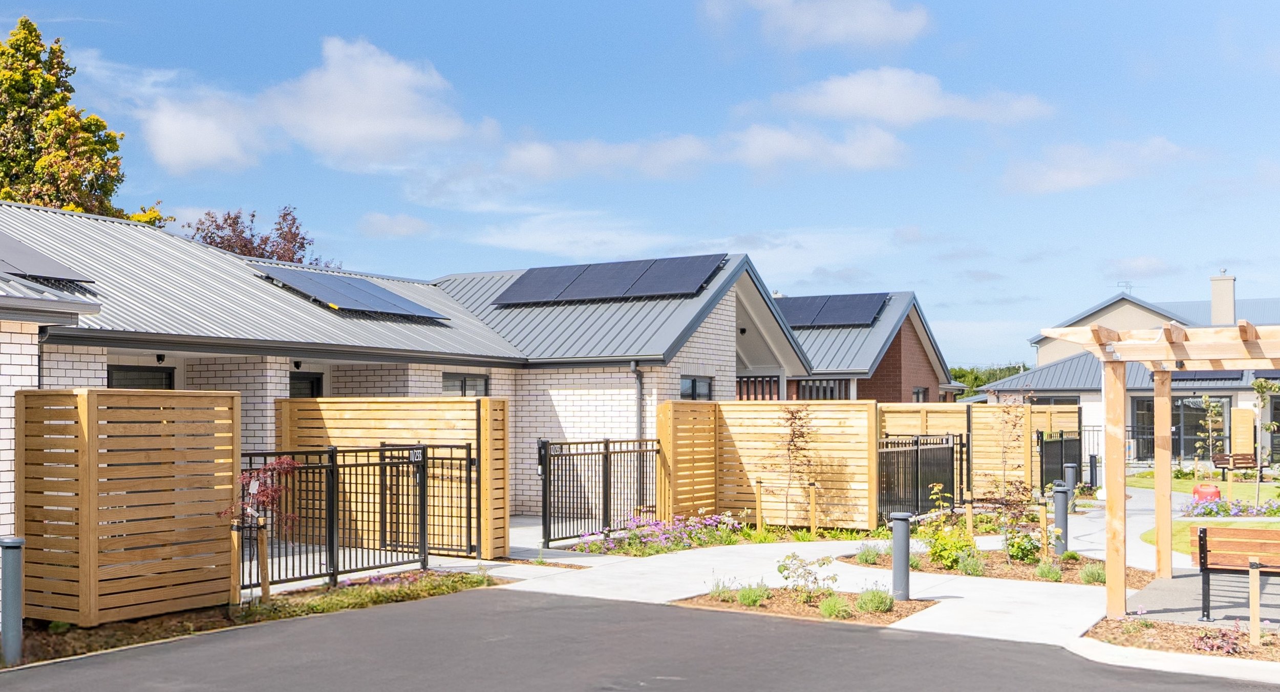 Exterior view of single-level homes with communal areas and planting.