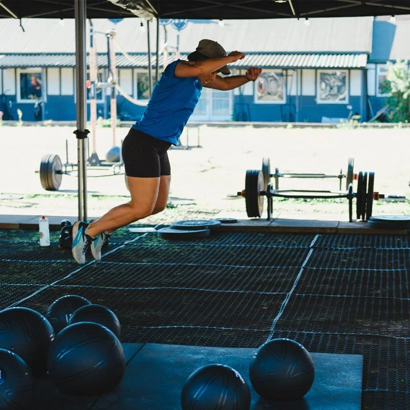 Yoked fitness member captured mid air doing a broad jump warm-up exercise