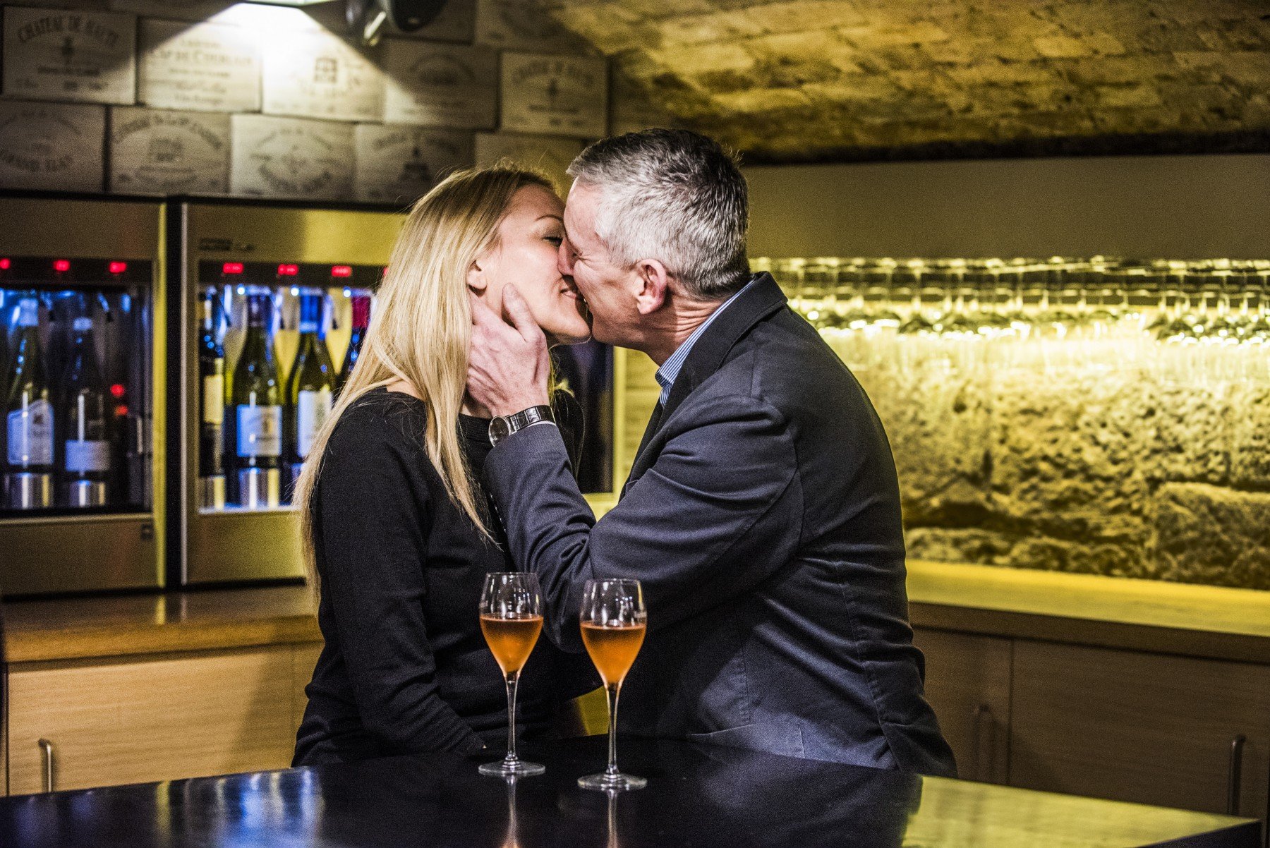 Man and woman kissing in bar with two drinks