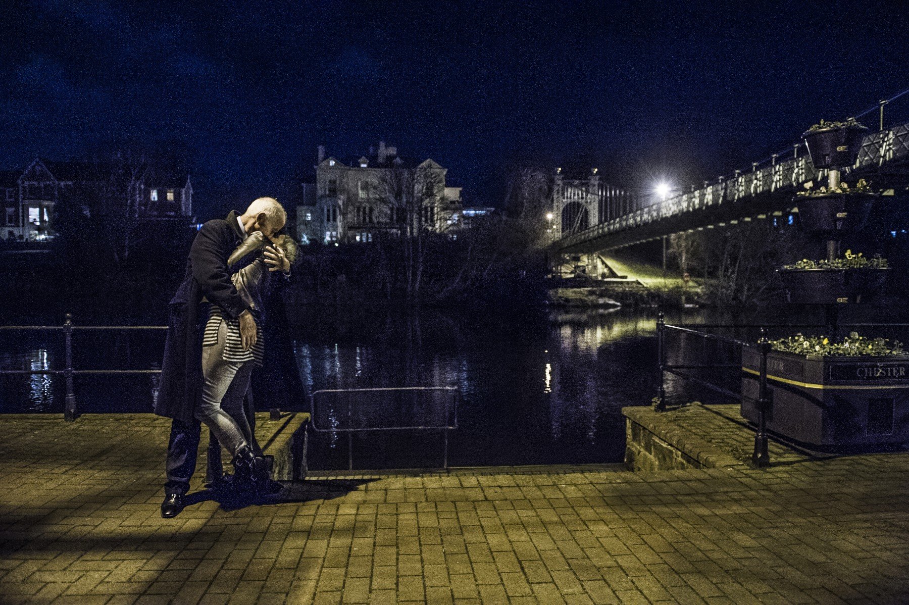 Man and woman kissing at night by the river
