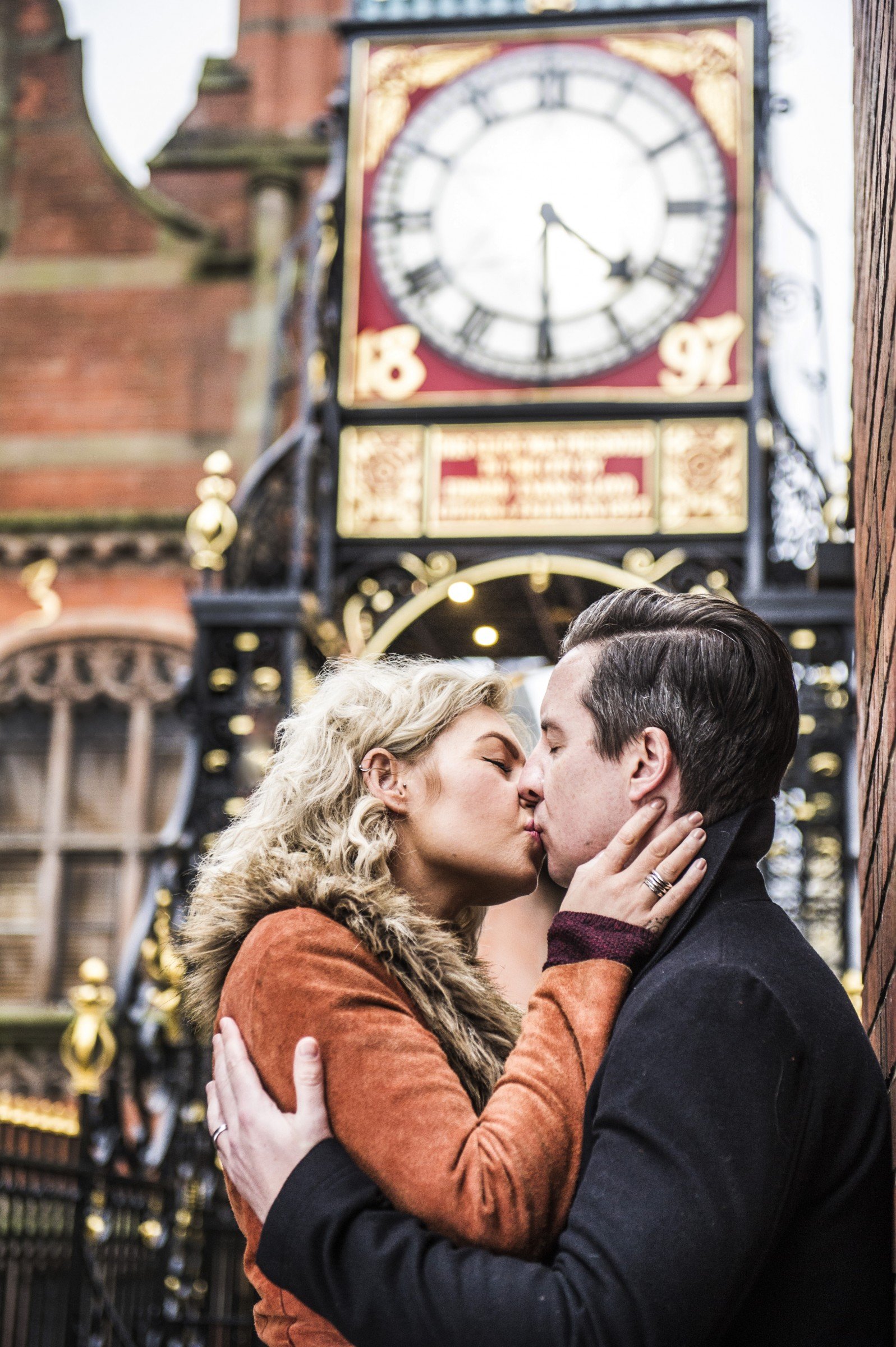 Man and woman kissing in front of Chester clocktower