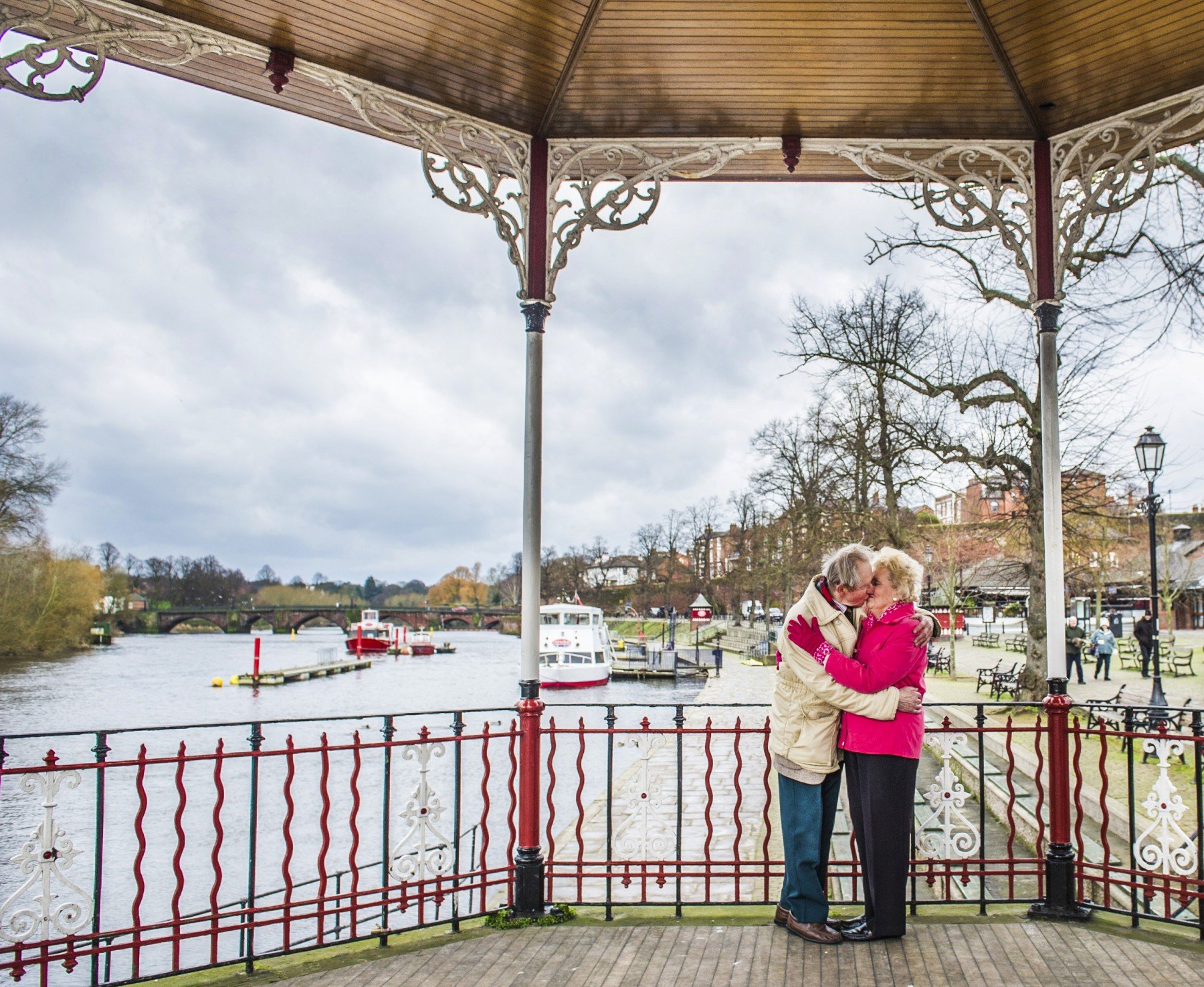Man and woman kissing by river in bandstand