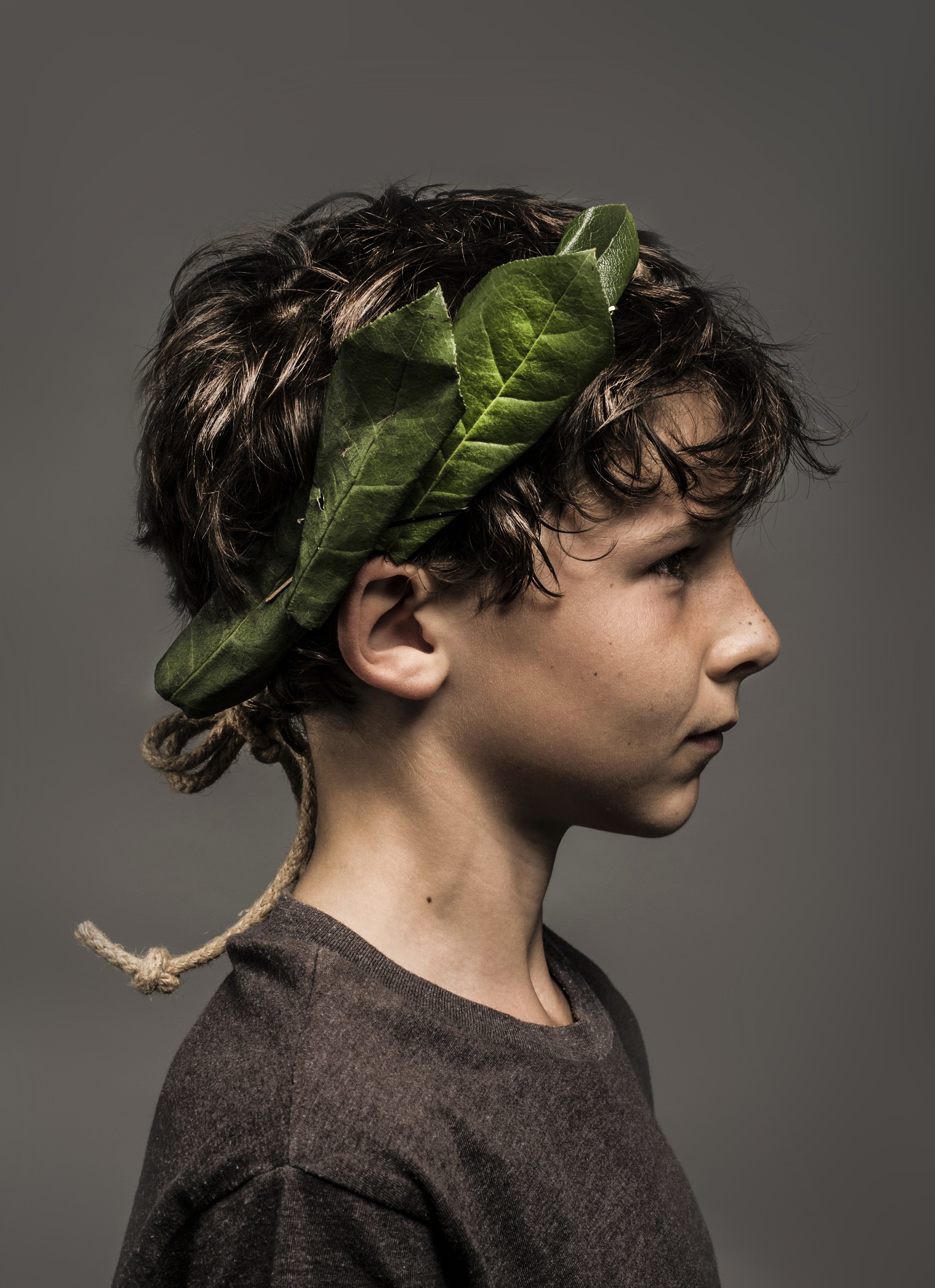 Young boy with dark hair wearing leaf crown
