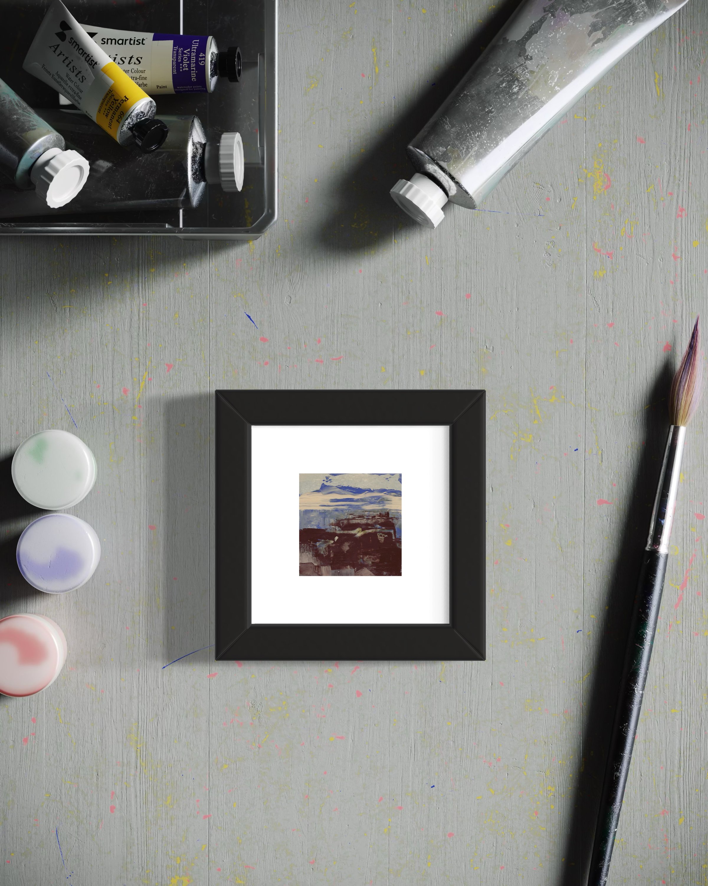 Framed miniature painting rests on artist's work surface.