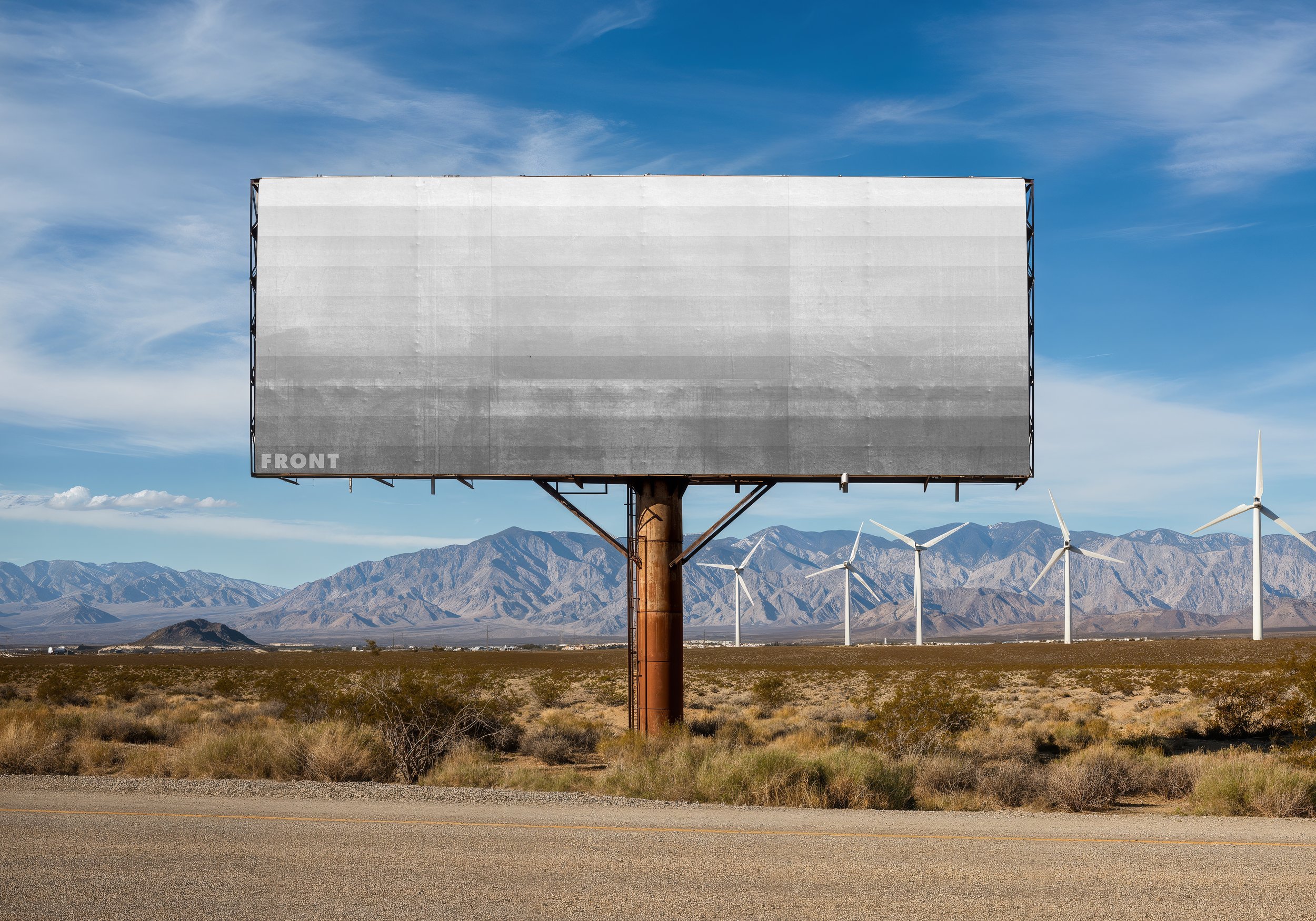FRONT blank outdoor billboard mockup in a desert setting with mountains and wind turbines in the background.