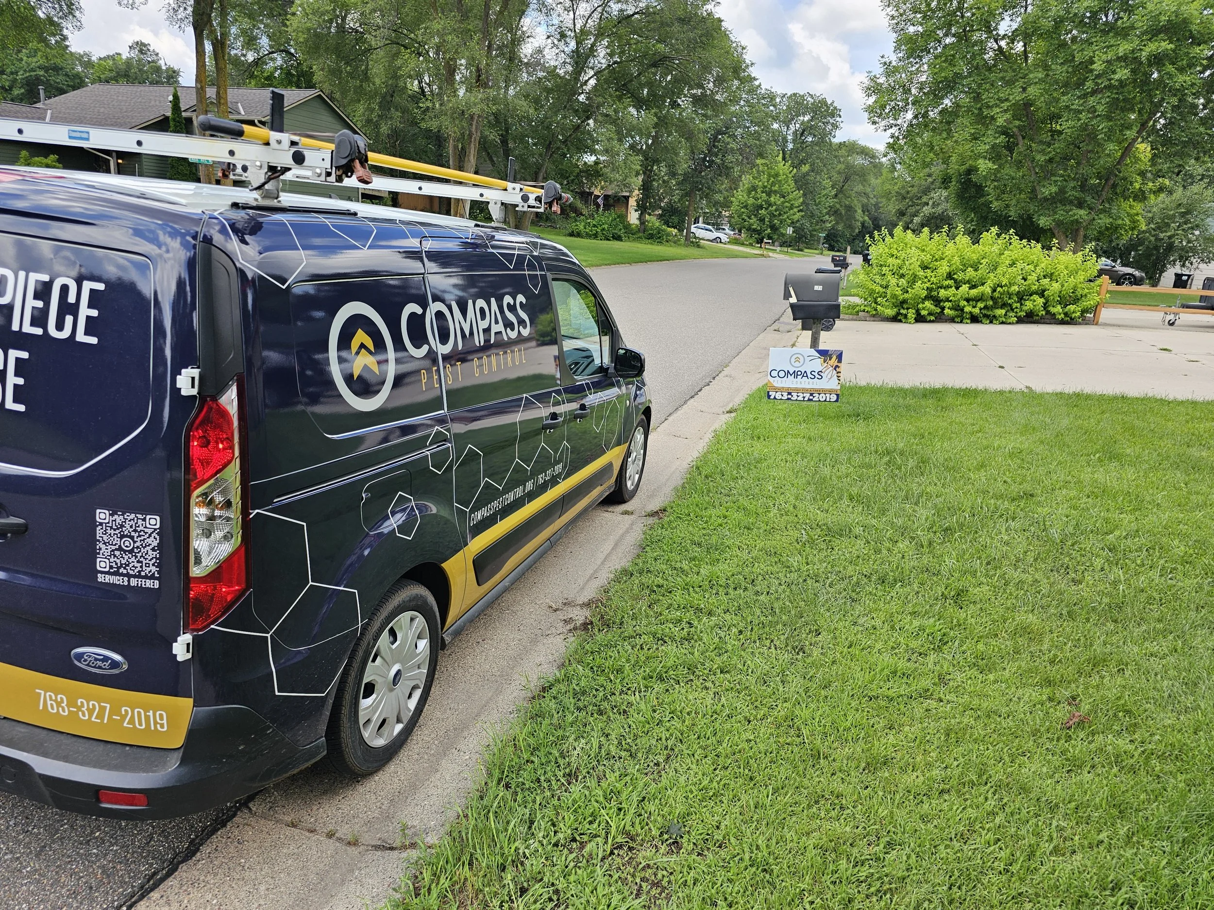 Compass Pest Control service van parked outside a Central Minnesota home, with a branded yard sign displayed at the curb.
