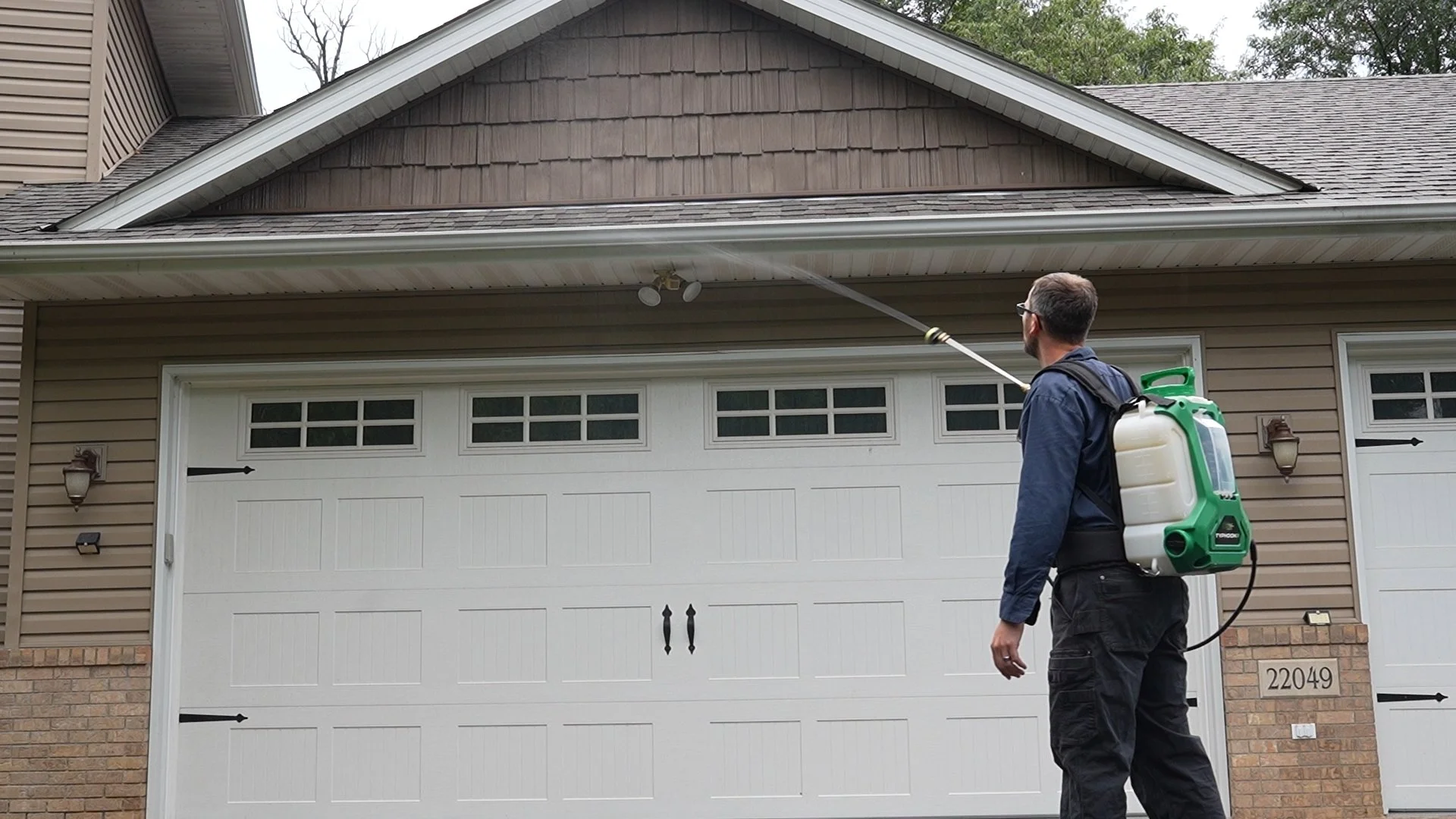 Compass Pest Control technician applying a targeted perimeter treatment along the exterior of a Central Minnesota home.