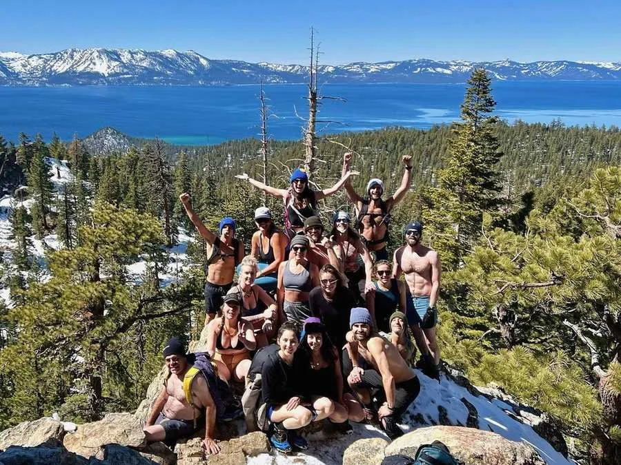 A large group celebrating on a rocky summit above Lake Tahoe