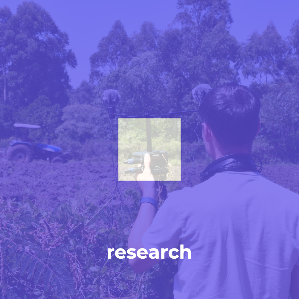 A person facing away from the camera audio recording an agricultural scene