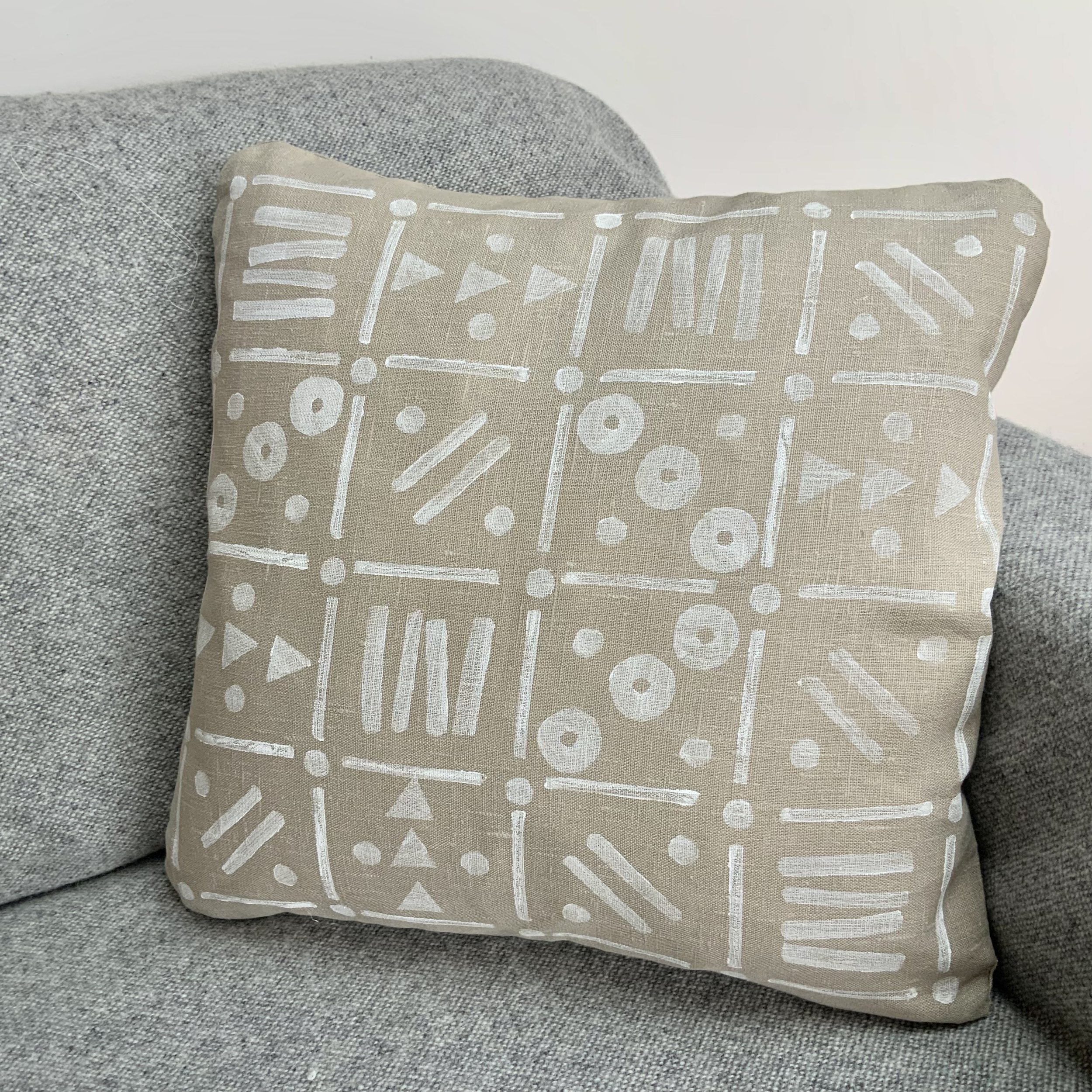 Hand-printed cushion by Susie Honnor using potatoes in Devon on 100% natural linen. 'White Grid' uses white ink with varying patterns in eachsquare of the grid. Viewed on sofa