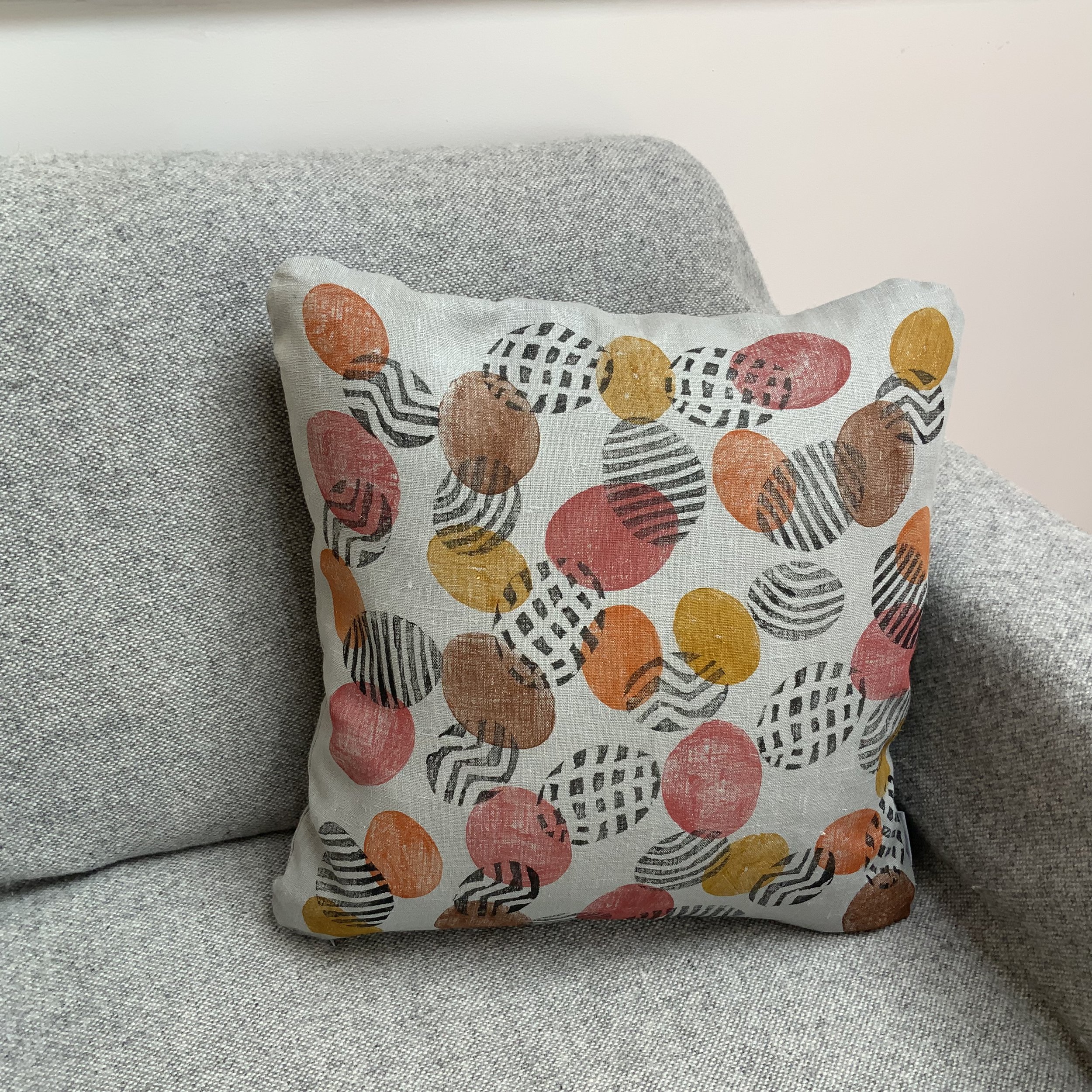 Potato print in black patterns with yellow spots on 100%grey linen. Cushion viewed on sofa.