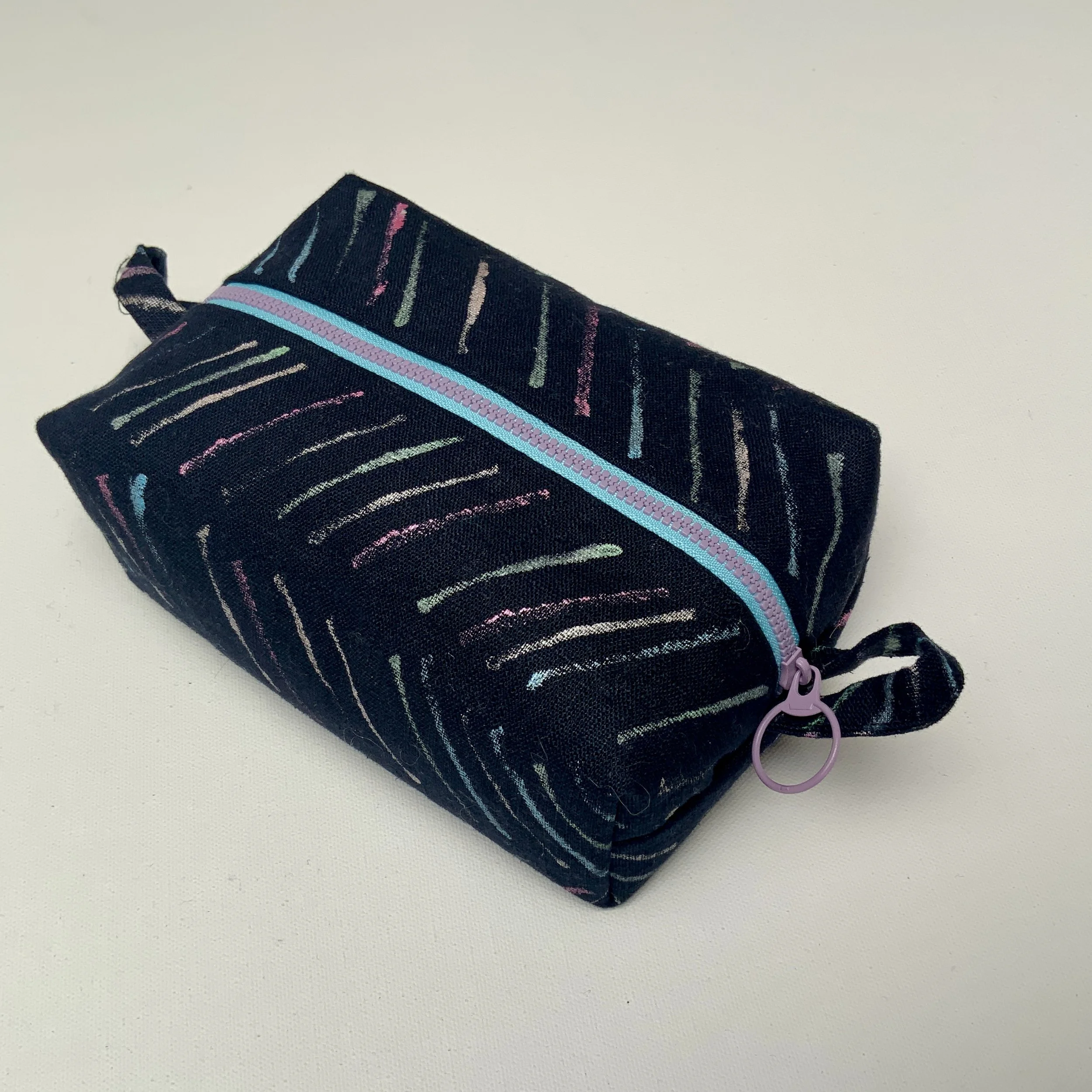 Hand printed boxy zipped pouch. Chevron motifs  printed onto black Ramie fabric. Fully lined and complete with contrasting feature zip.