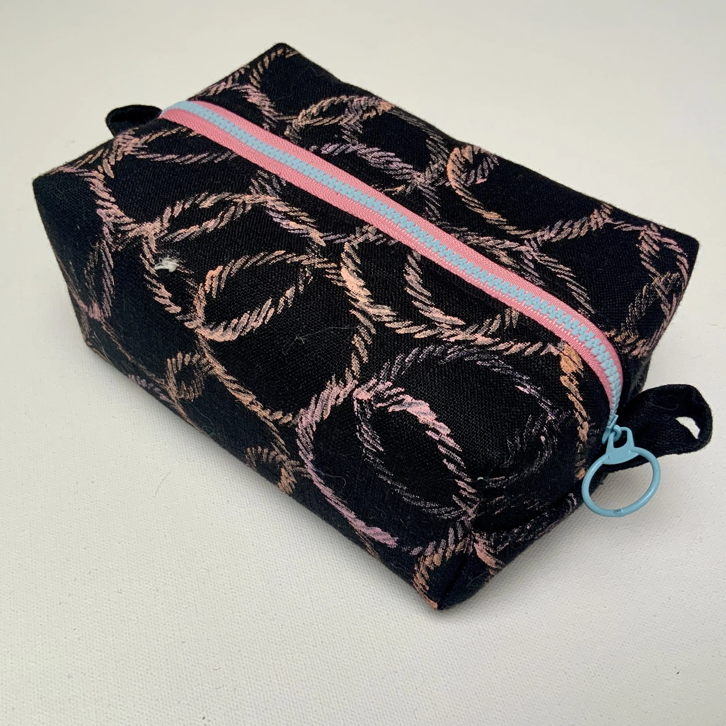Hand printed boxy zipped pouch. Circle motifs printed onto black Ramie fabric. Fully lined and complete with contrasting feature zip.