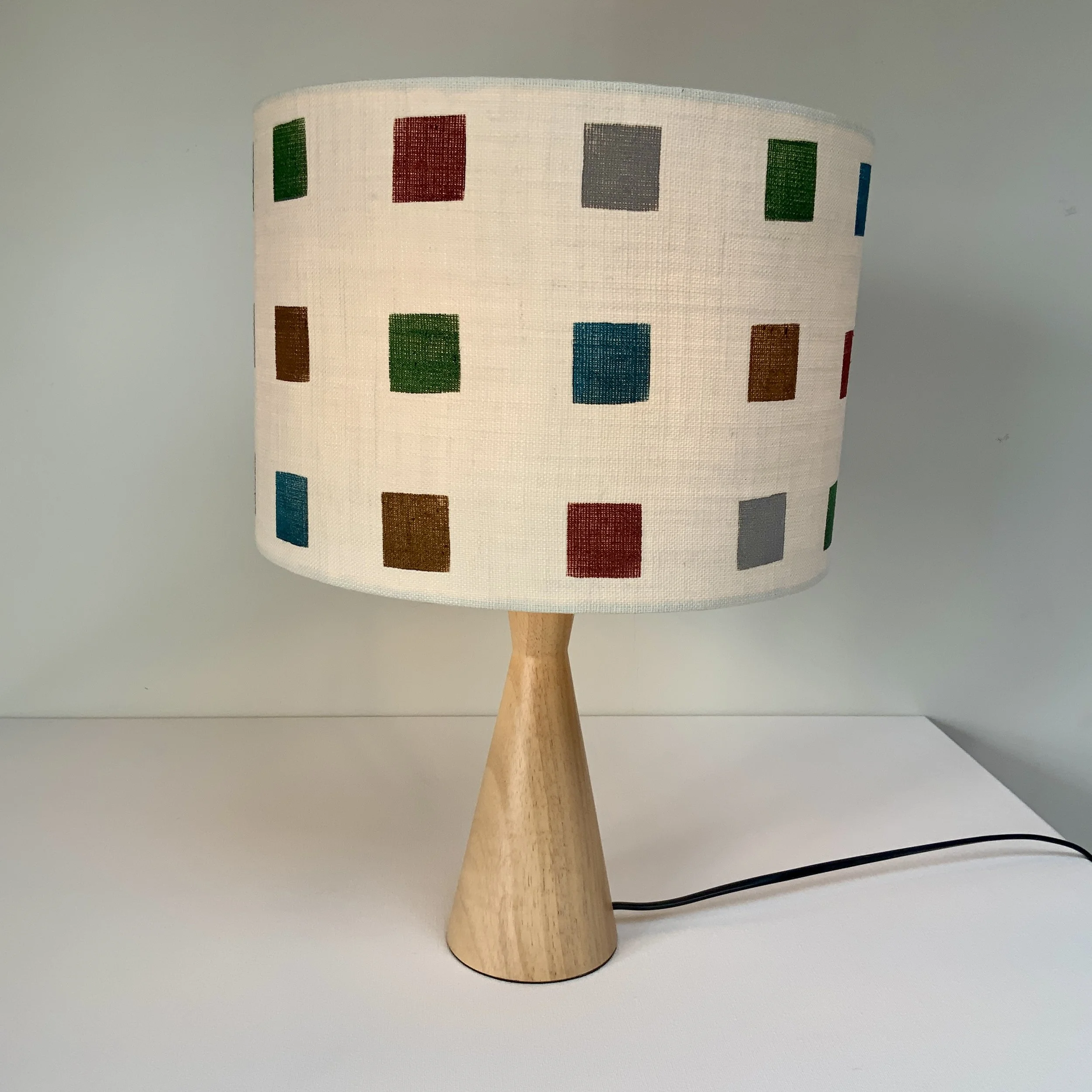 Hand printed lampshade in geometric pattern using rich colours in red, blue, green and brown.