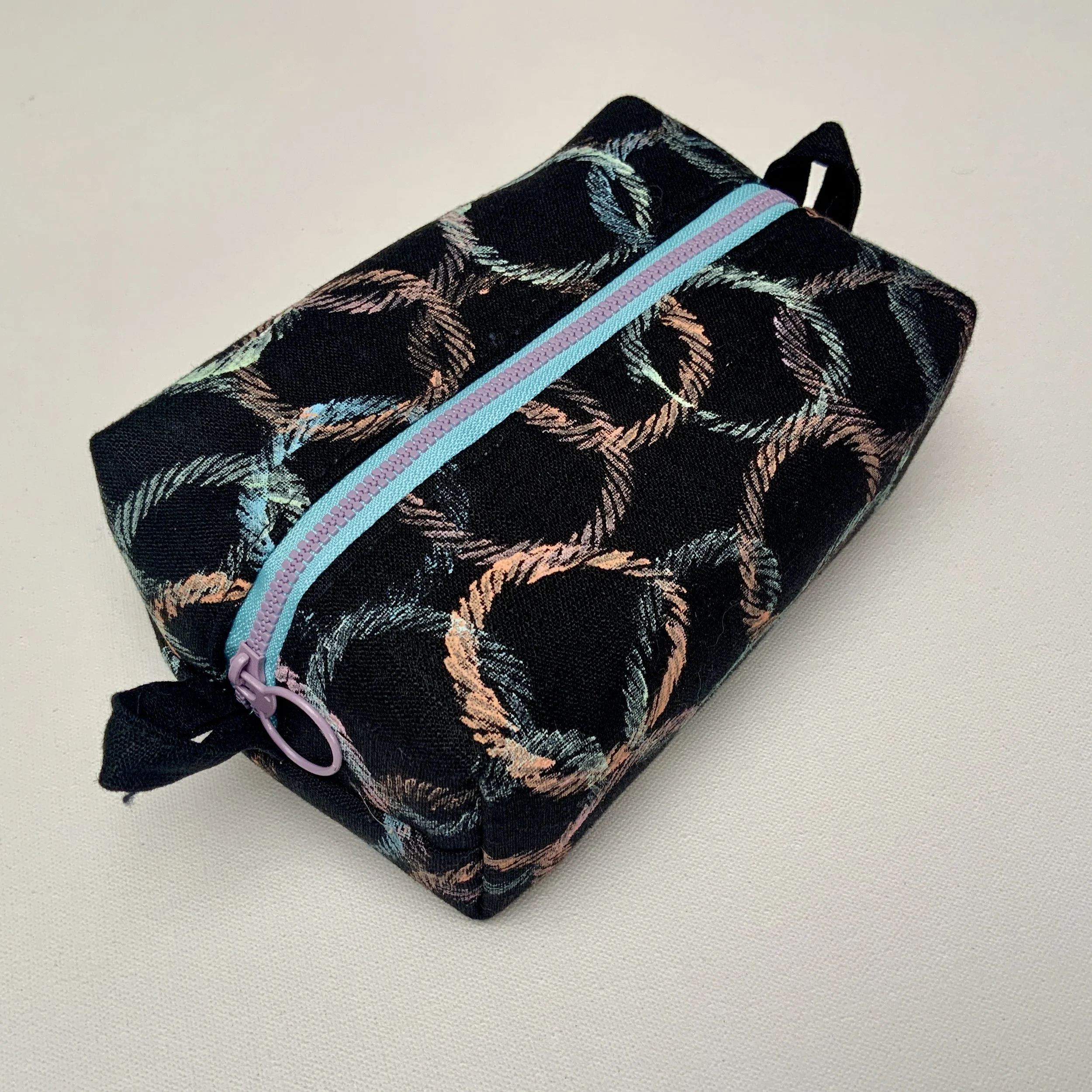 Hand printed boxy zipped pouch. Circle motifs printed onto black Ramie fabric. Fully lined and complete with contrasting feature zip.