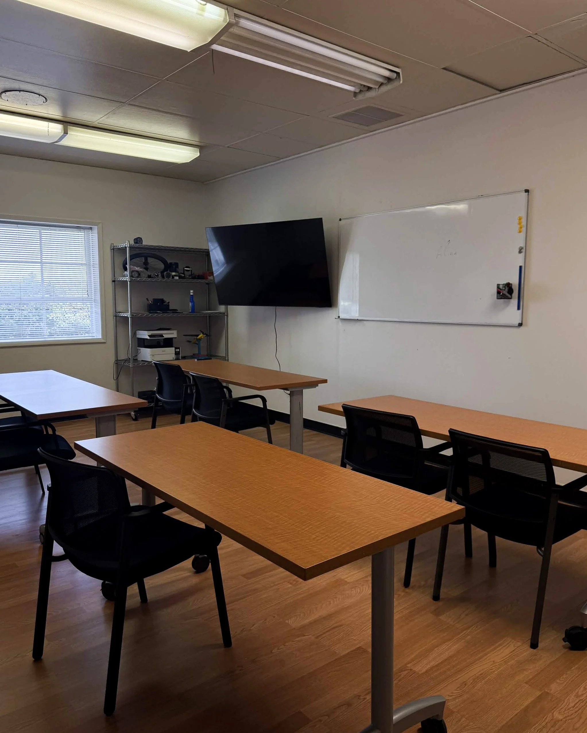 Classroom with students seated at desks, watching a presentation on a screen, with model airplanes and a drone hanging from the ceiling.