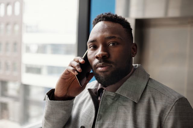 A black man in a coast on a cell phone