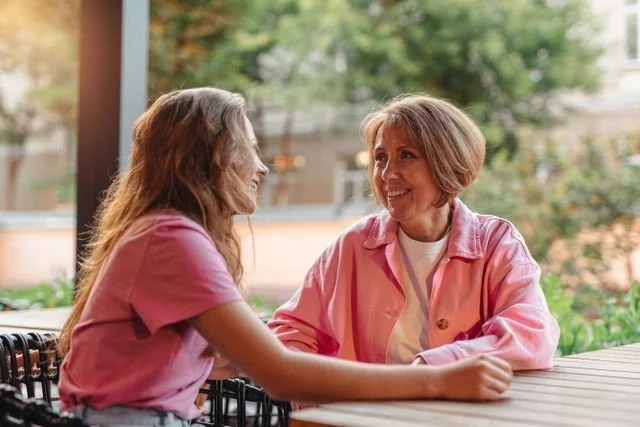 two women wearing pink talking outside