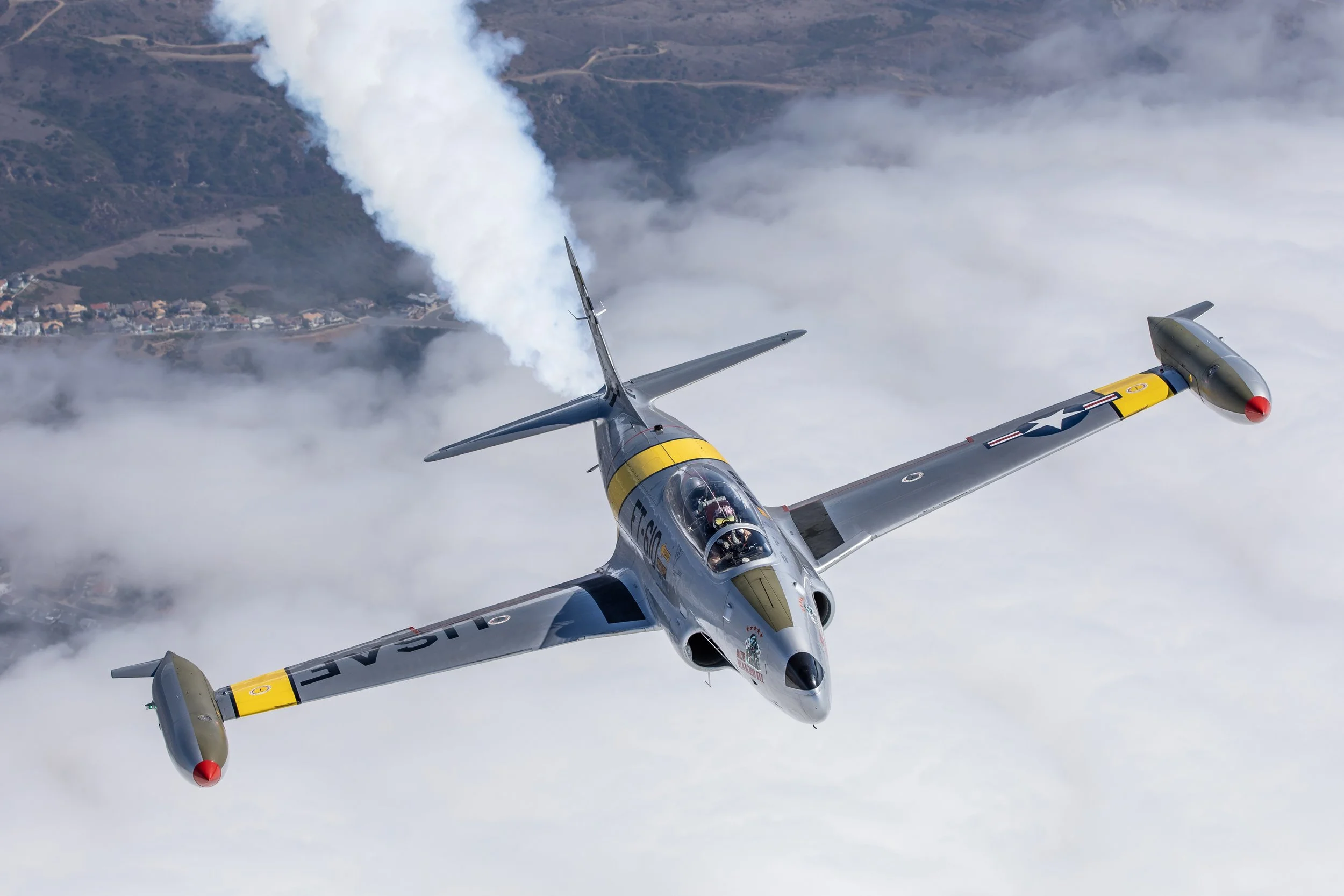A military jet flying through the sky with smoke.