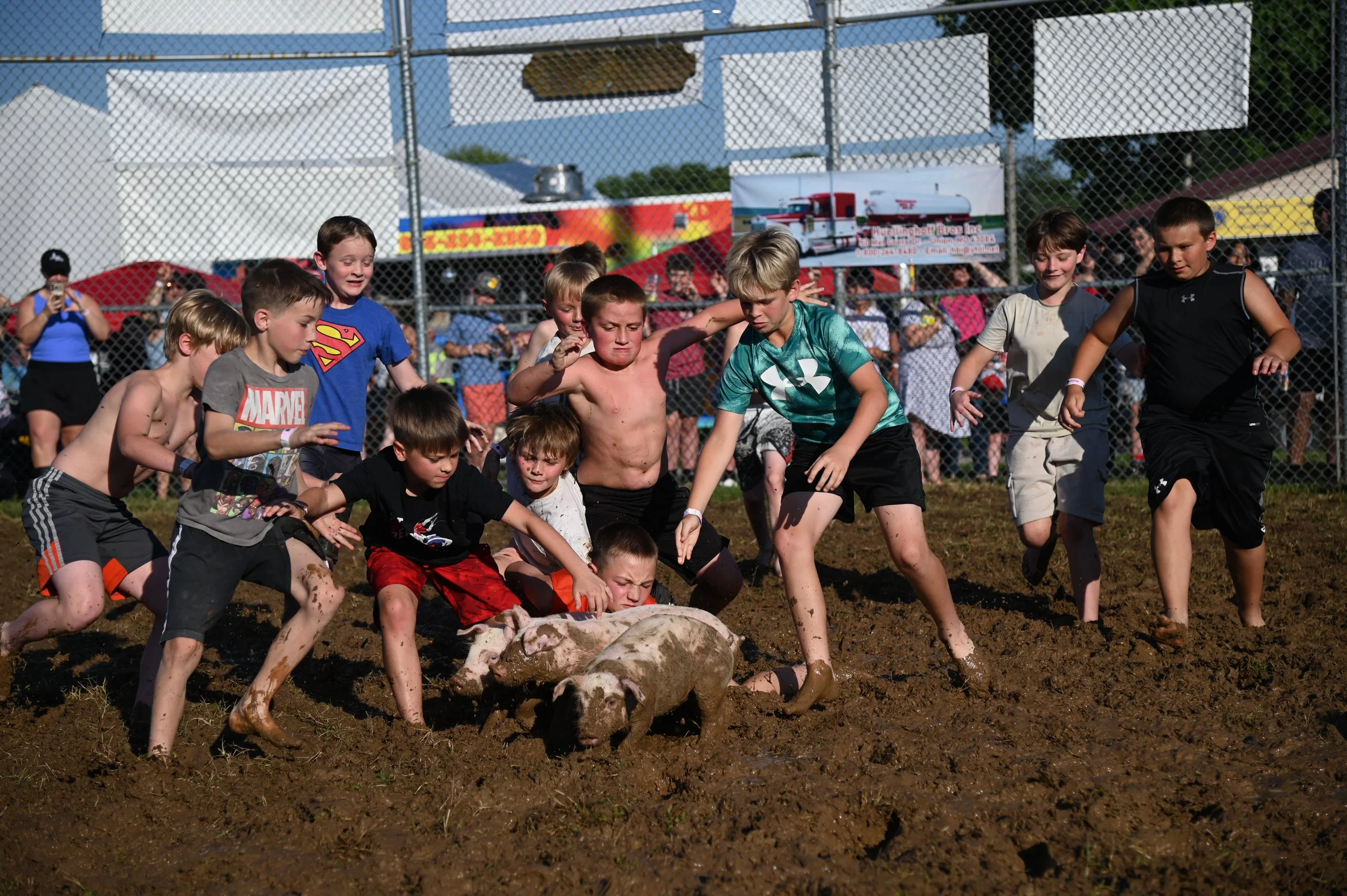 Boys get dirty in the mud while participating in the Pig Scramble at the Franklin County Fair in Union, Mo. on Thursday, June 19, 2025. The winner must grab the piglet by the hind legs and drag it to the finish line. 