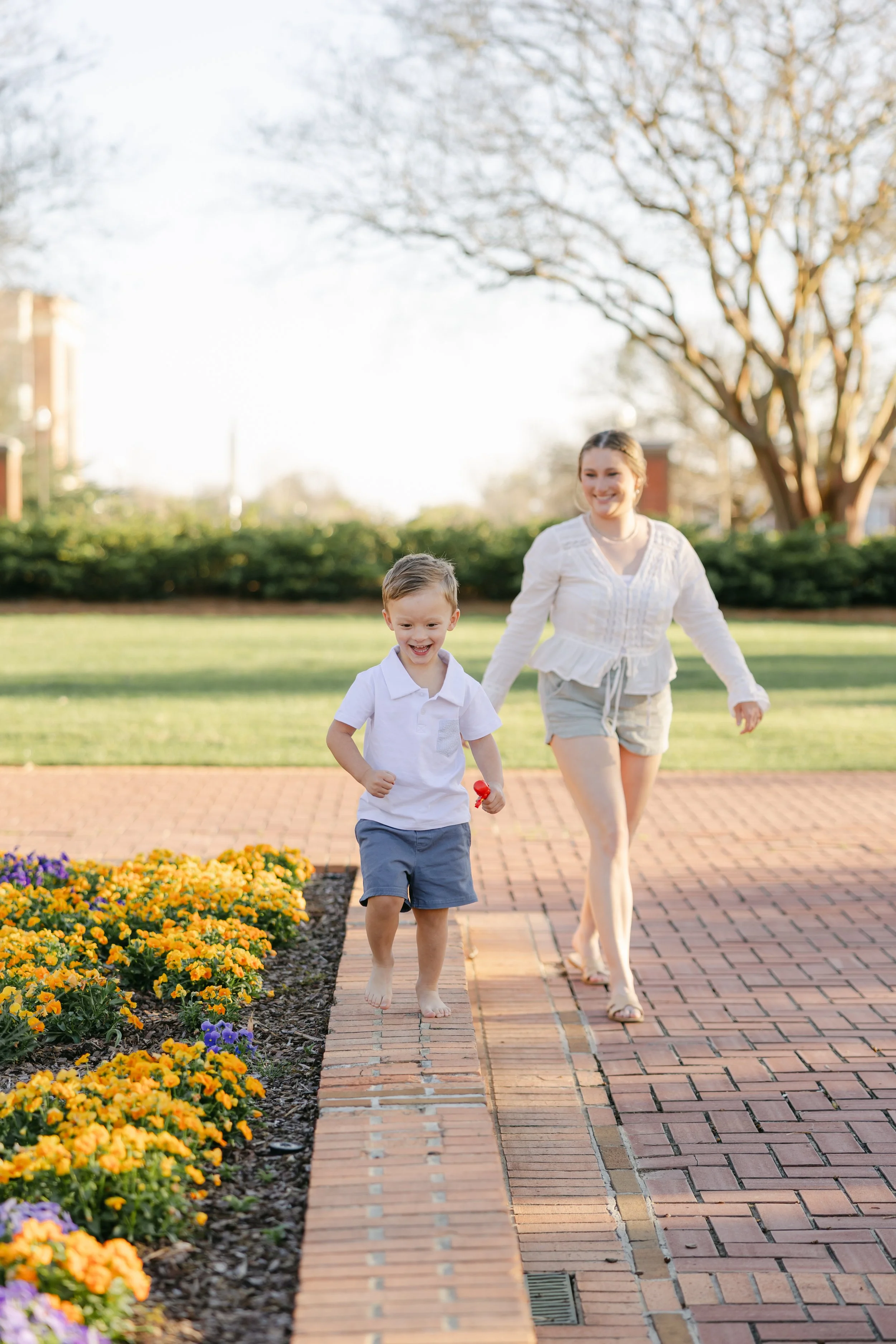 Student-Mom and her baby walking around and playing on campus next to some flowers