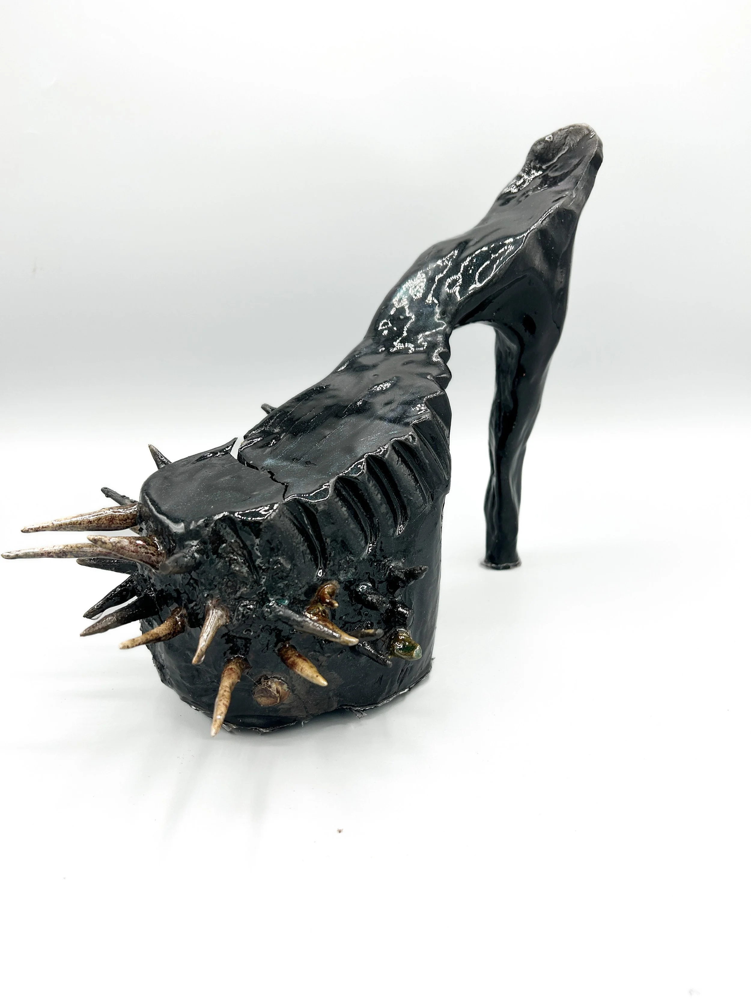 A crafted, black spiky heel on a white background