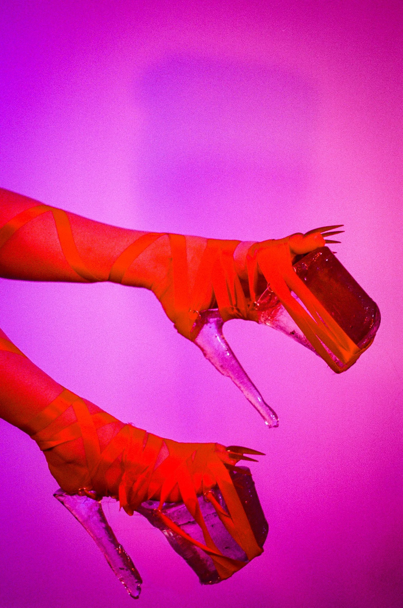 A photo of heels made of red lace with a grainy pink background