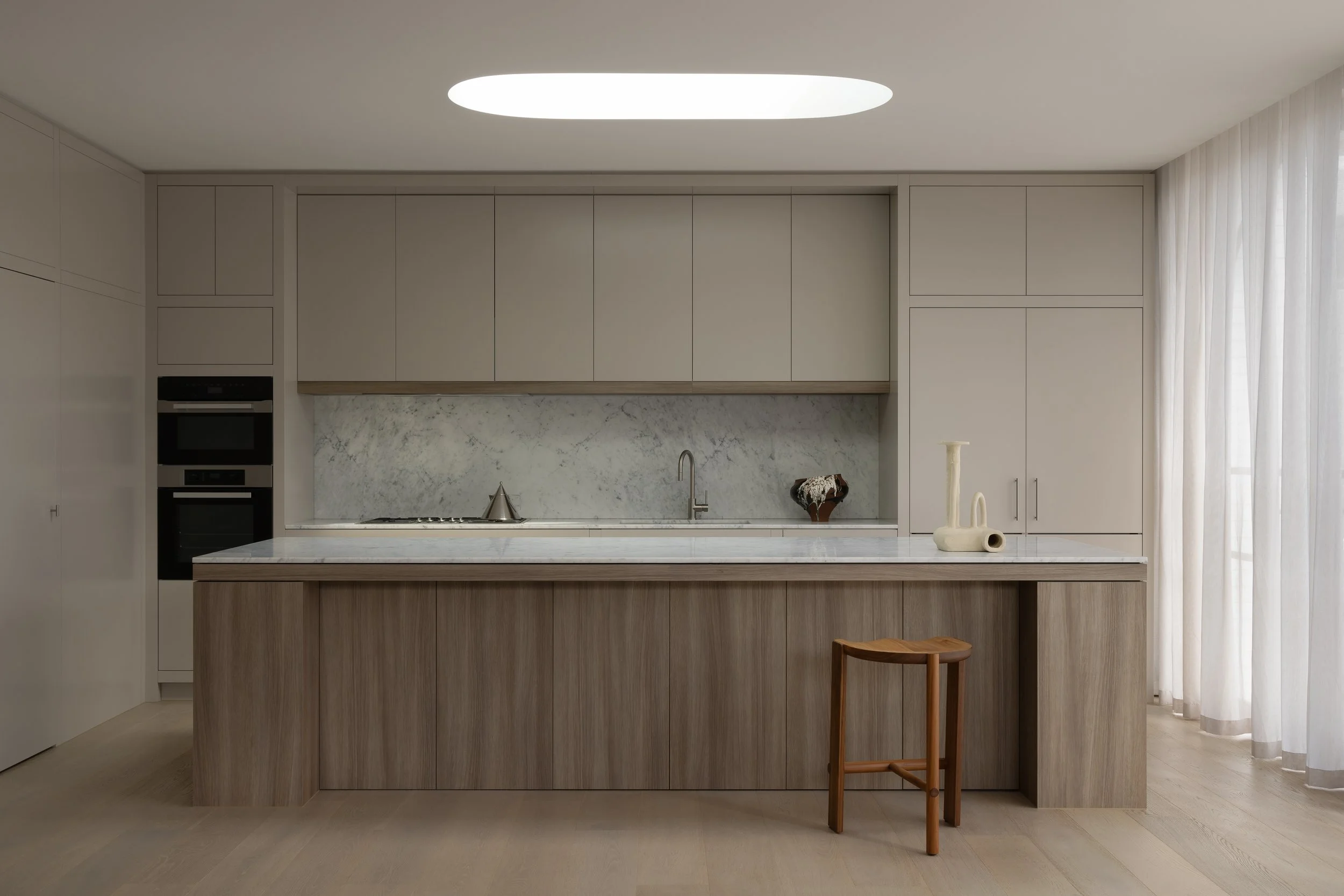 Prahran House kitchen with long timber island, skylight and stone splashback