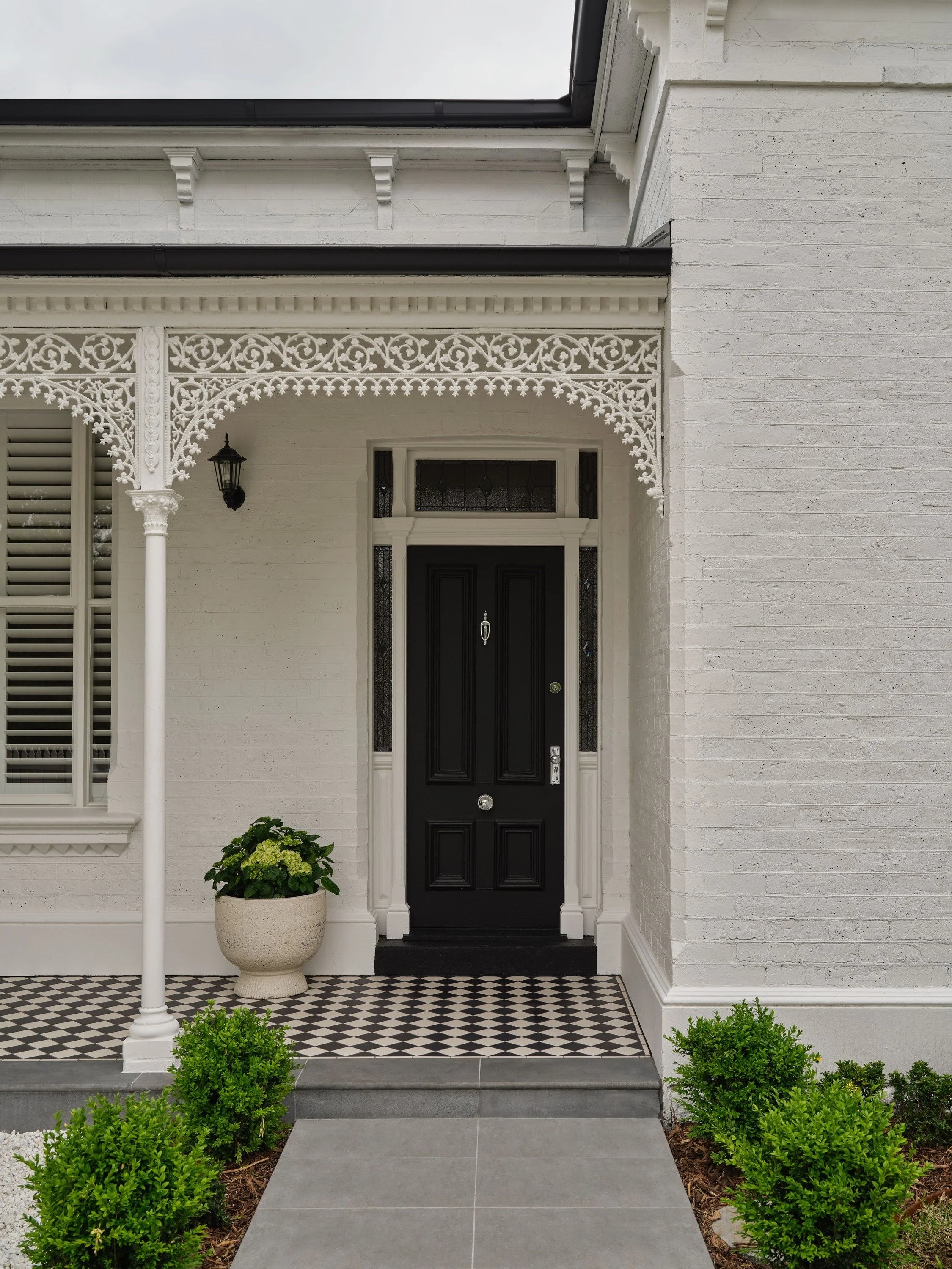 Windsor House Victorian front entry with black door, lacework and tiled verandah