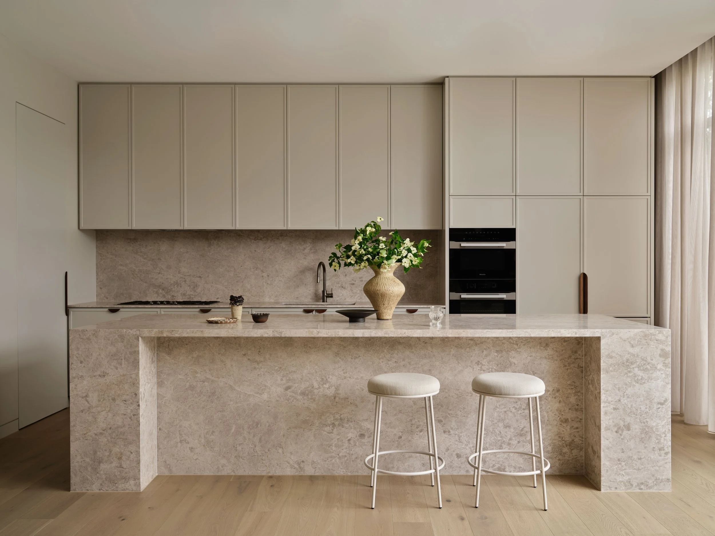 Windsor House kitchen with stone island, two stools and full-height cabinetry