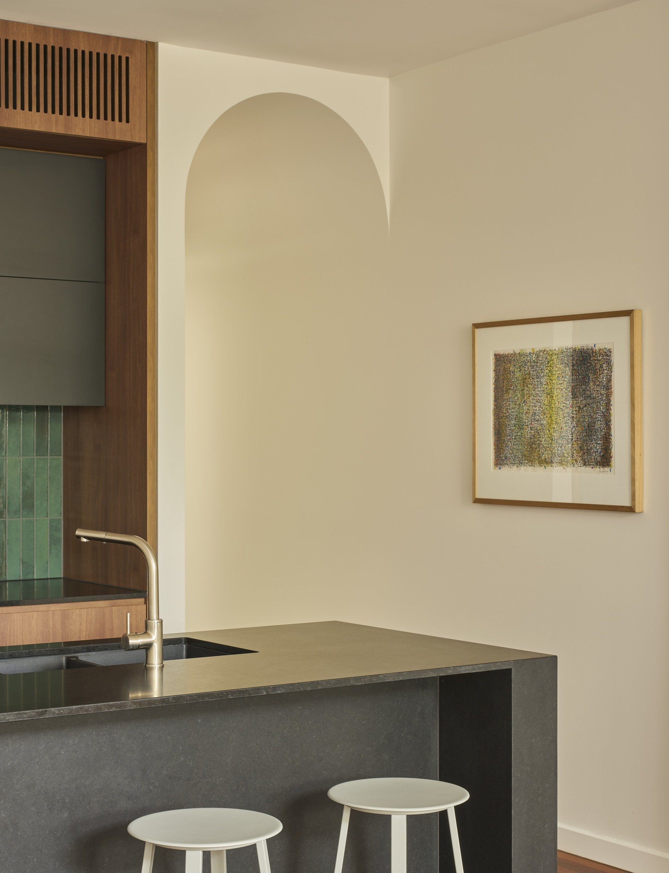 Carlton North House kitchen island beside an arched opening and framed artwork