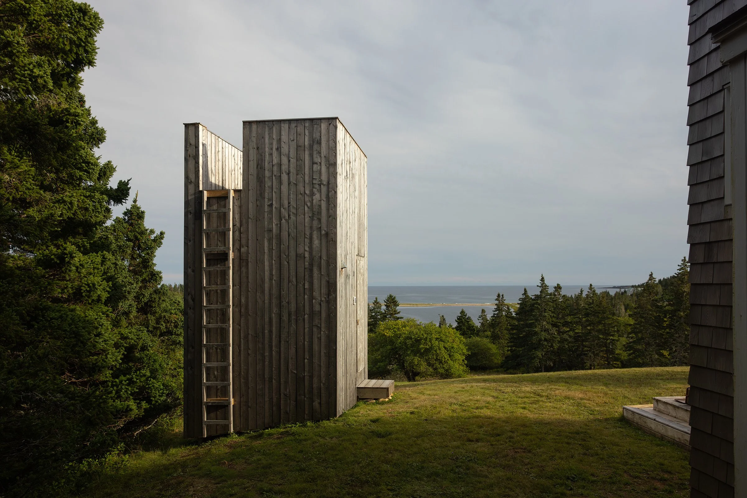 Modern cedar sauna by Place of Work overlooking a field and the Atlantic coast of Nova Scotia